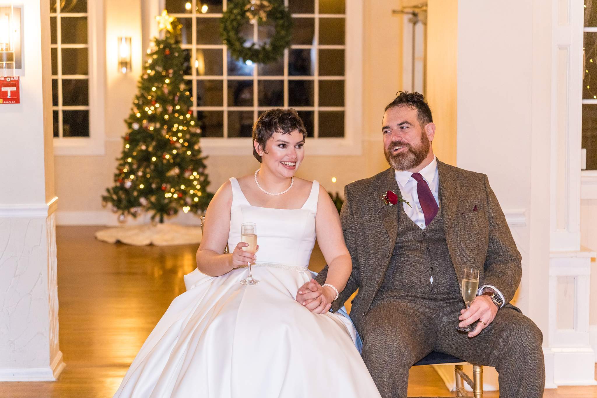 Couple seated by a Christmas tree during toasts at their reception