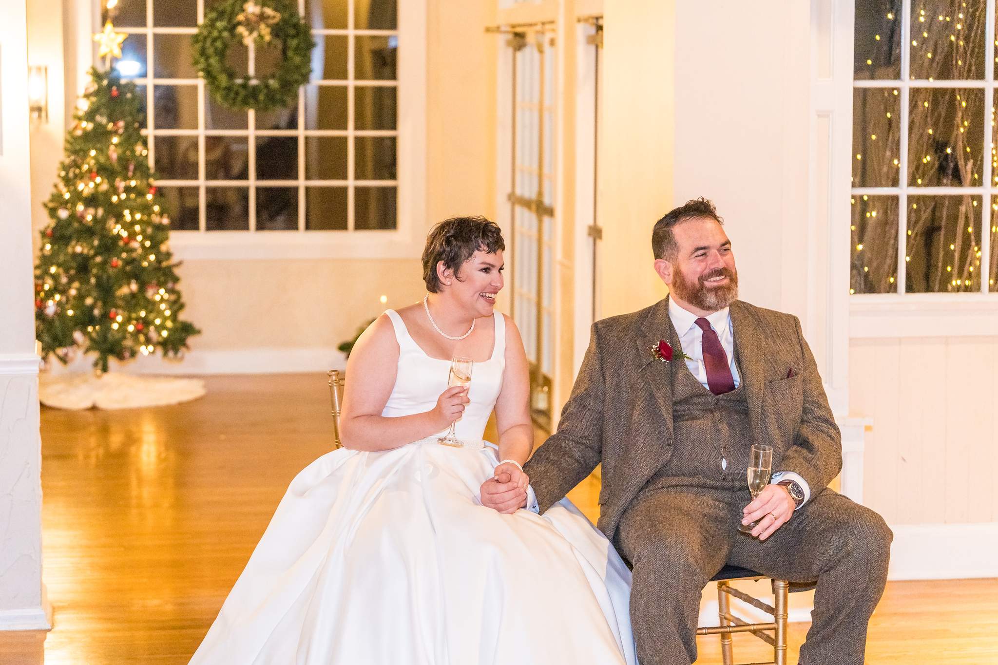 Couple laughing during toasts at a December wedding reception