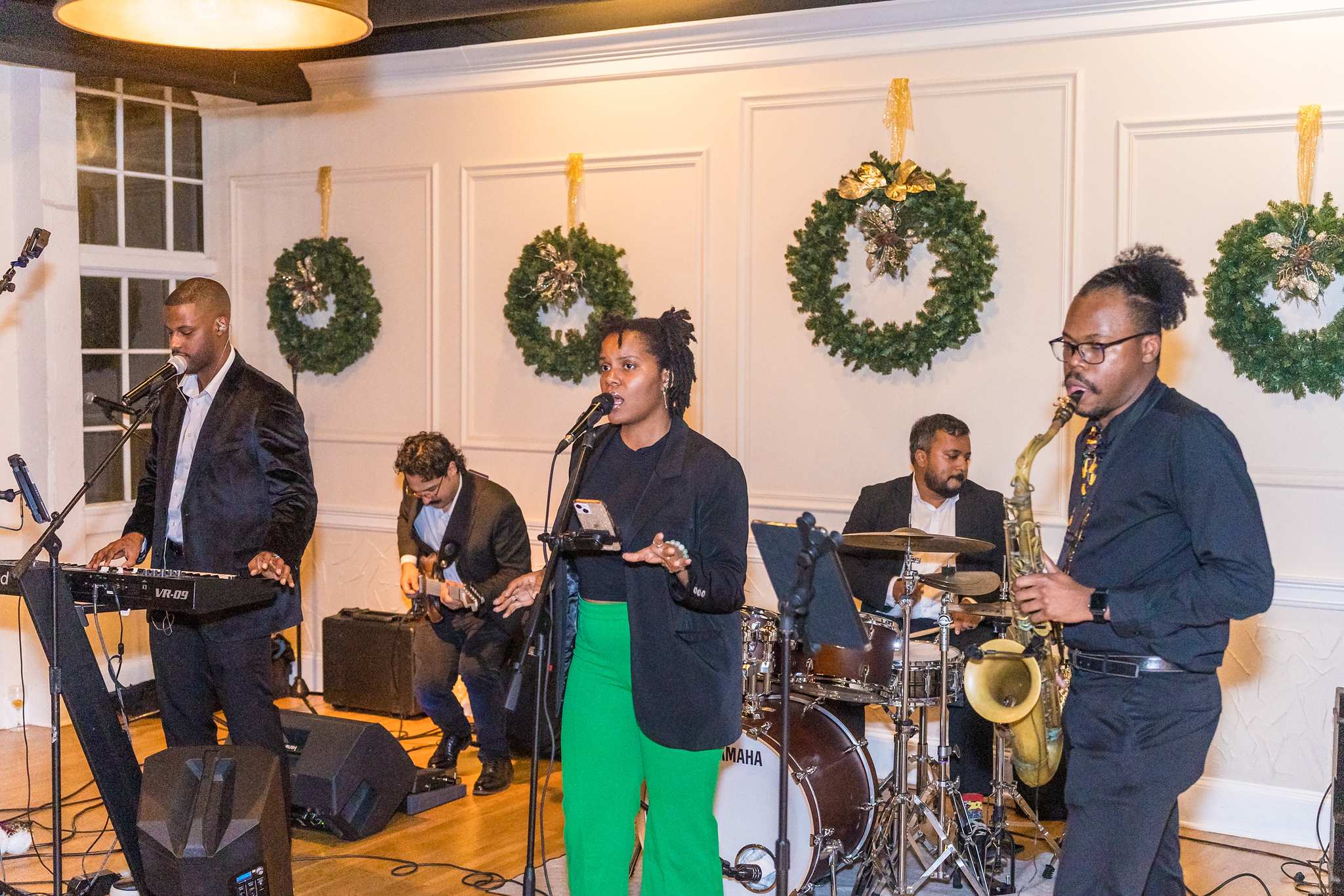 Live band playing in front of wreaths at a Christmas wedding reception