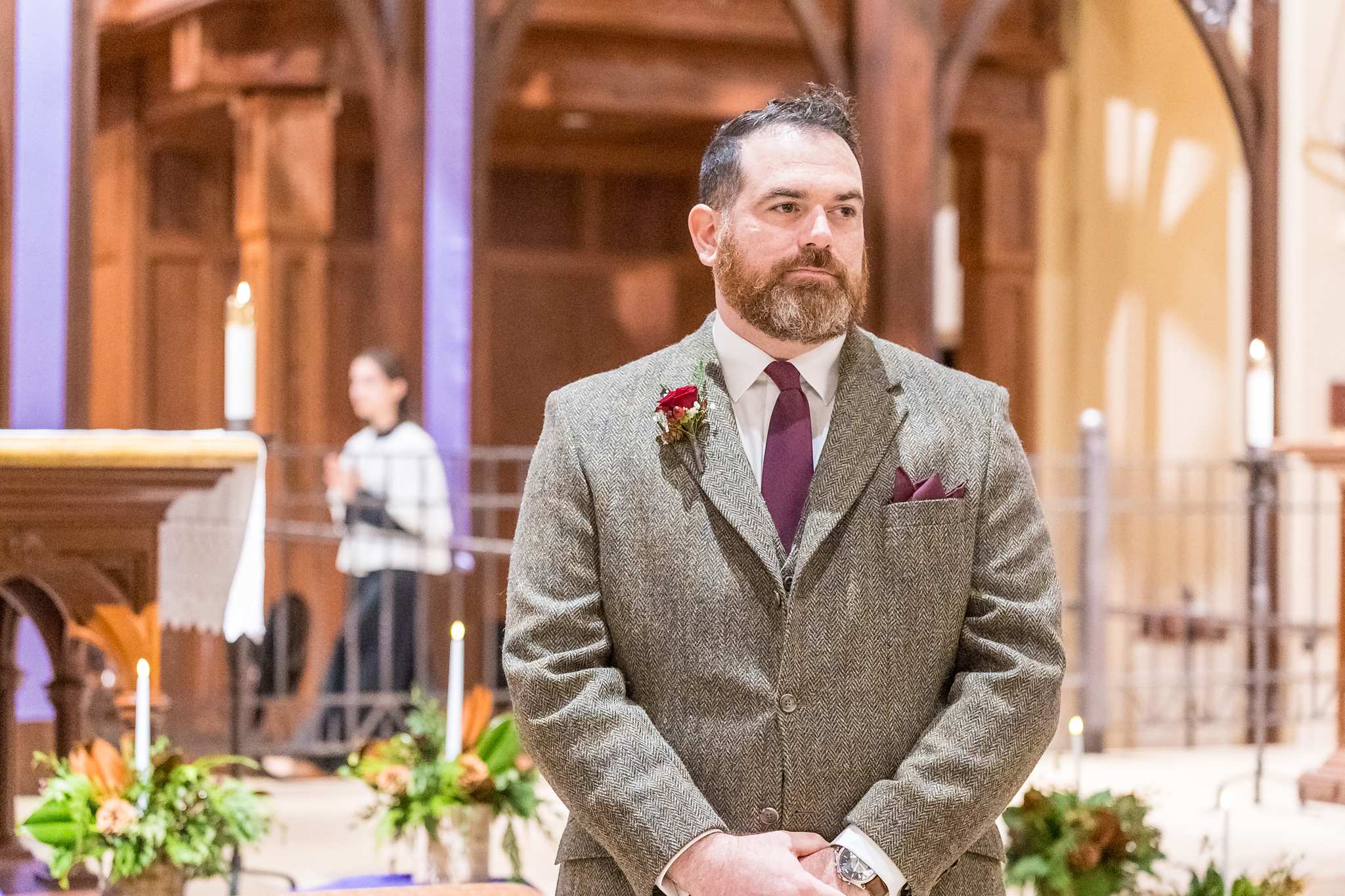 Groom waiting at the front of a decorated church before a Christmas wedding