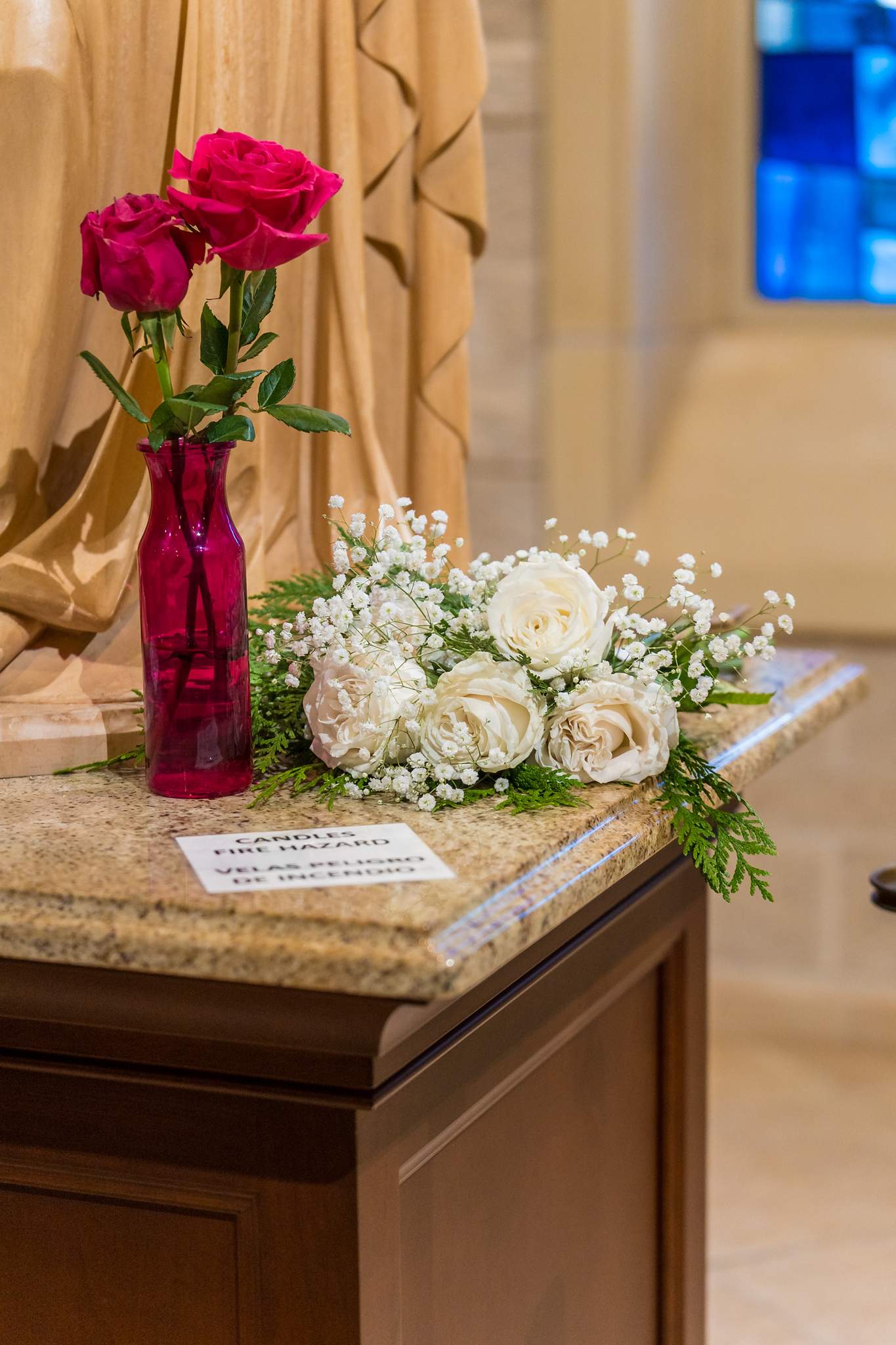 Red roses and white flowers on a stand inside a church for a Christmas wedding