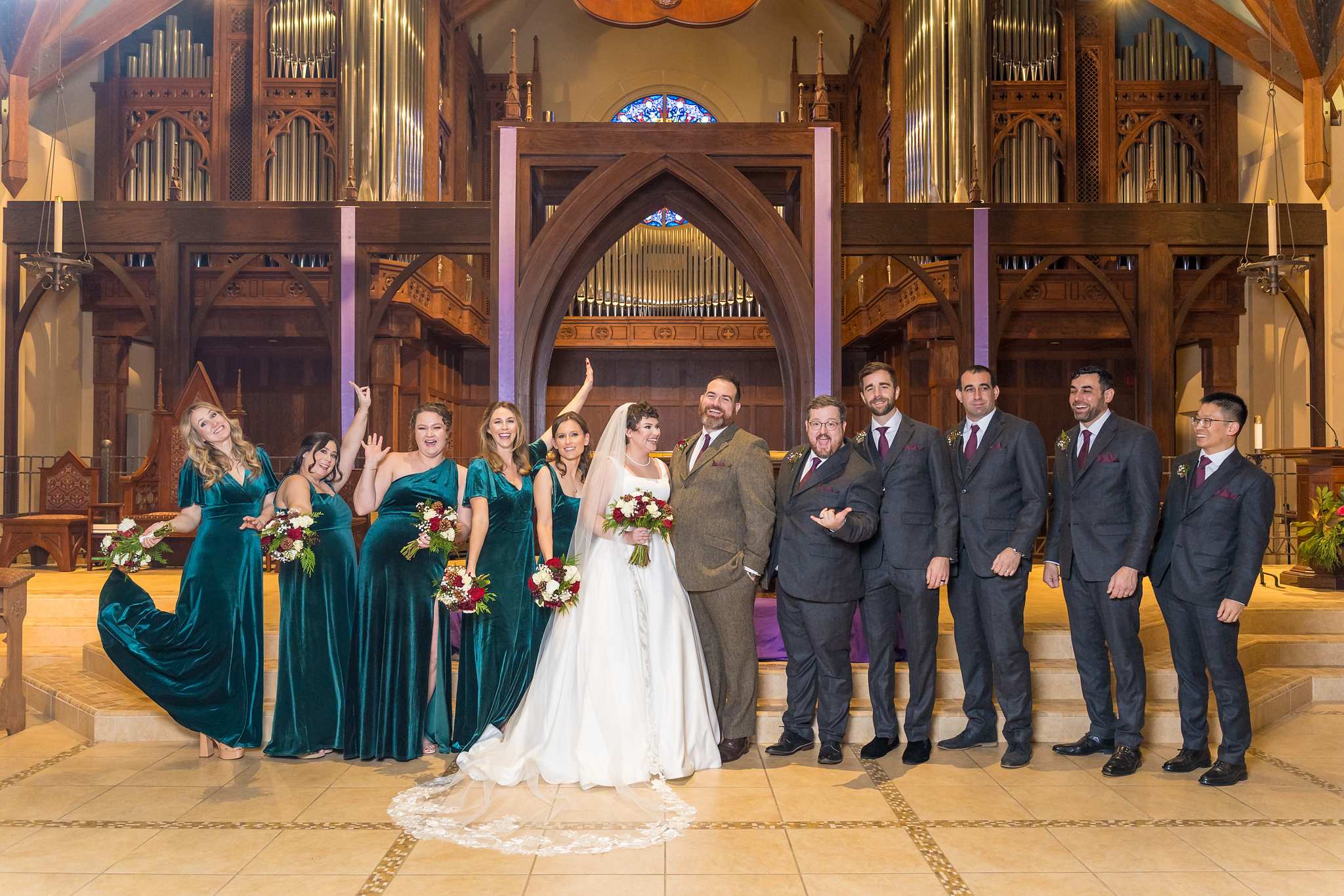 Wedding party in green velvet and dark suits celebrating at a church altar