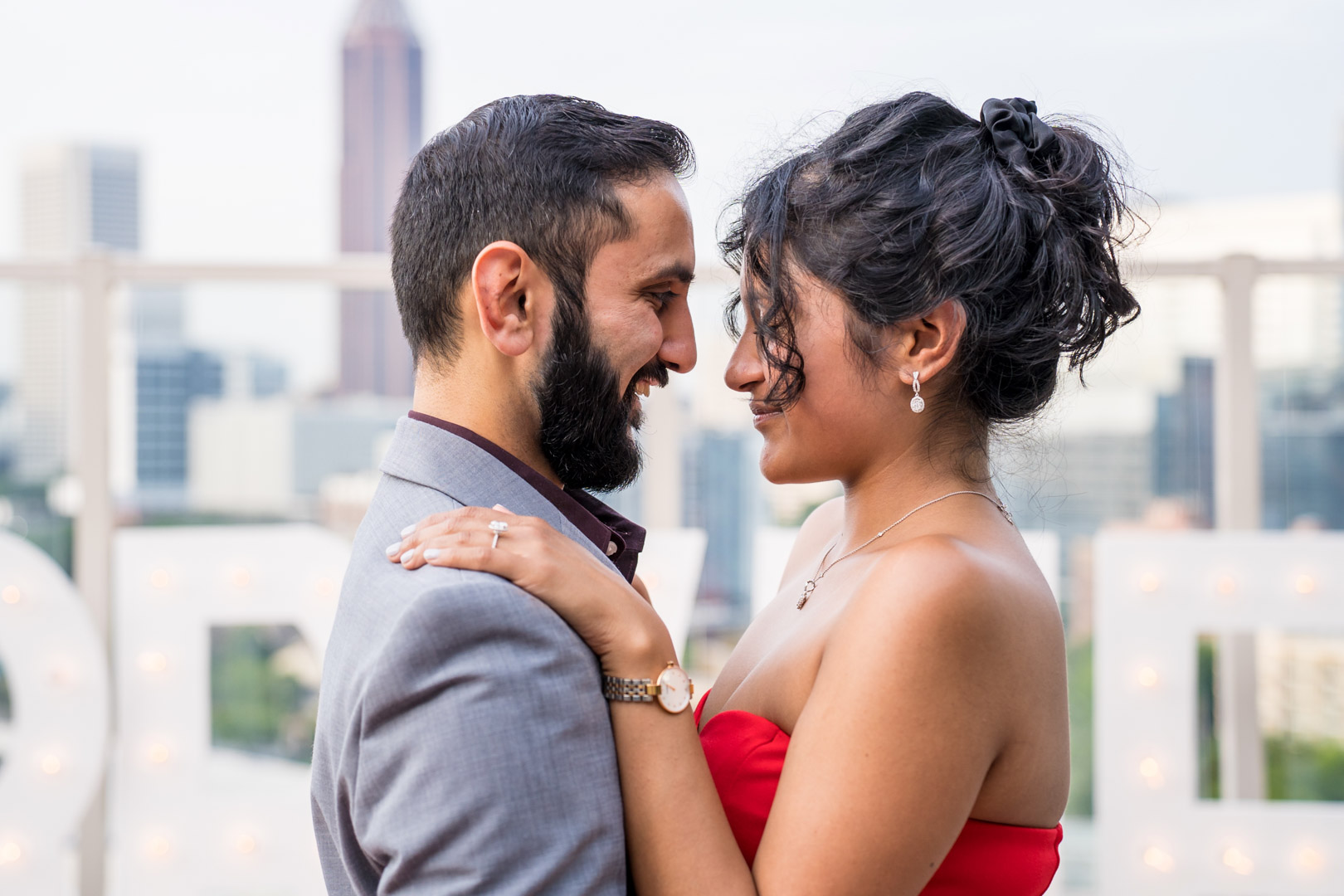 Engaged couple embracing and smiling at each other during portraits after their rooftop proposal
