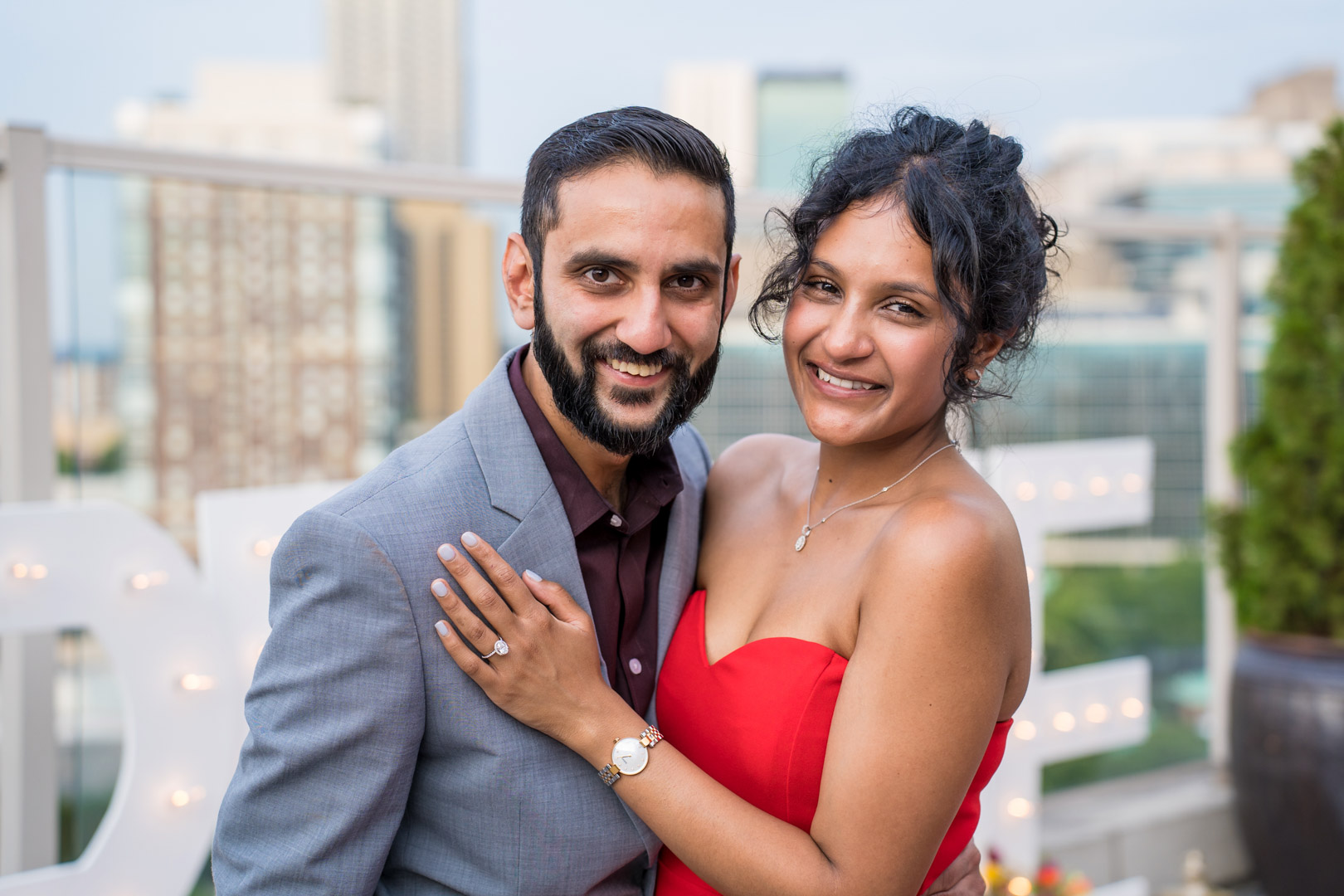 Engaged couple smiling at the camera during post-proposal portraits on an Atlanta rooftop