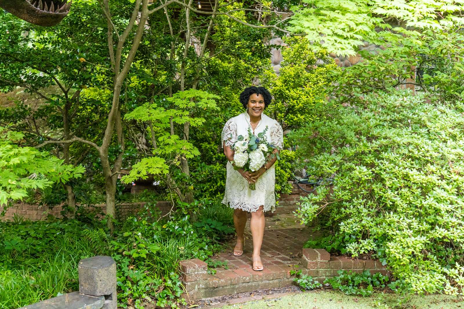 Bride walking through a garden to her elopement ceremony