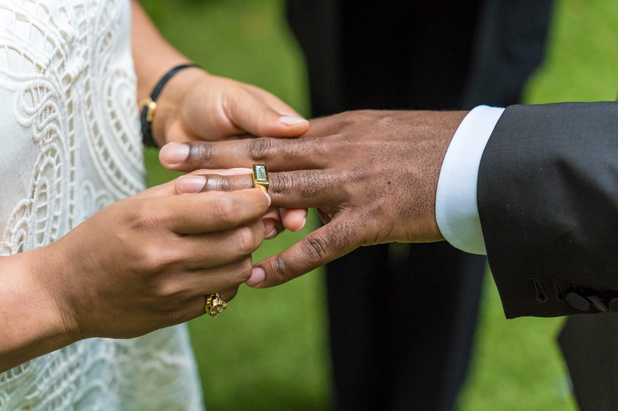 Close up of the groom placing the ring on the bride’s finger