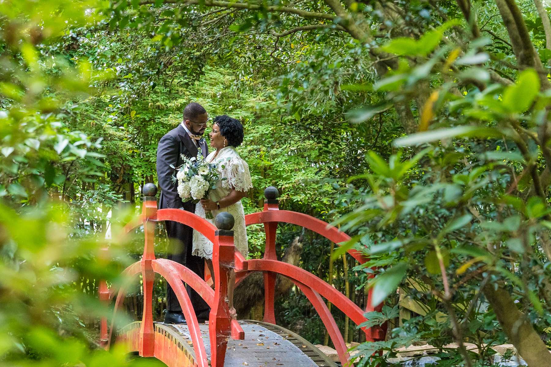 Couple on a red garden bridge after their elopement