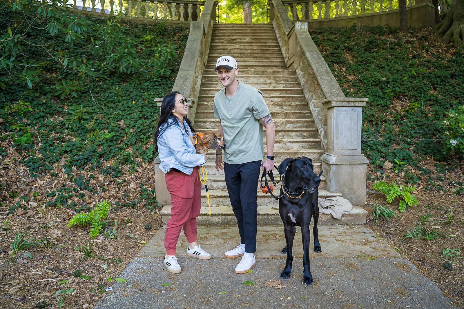 Newly engaged couple at the base of the stone staircase at Cator Woolford Gardens with their leashed Great Dane