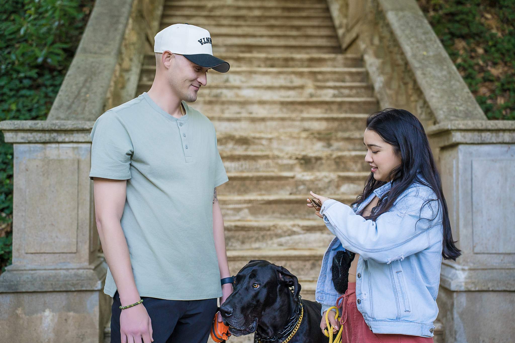 Couple sharing a quiet moment with their black Great Dane in front of the stone staircase at Cator Woolford Gardens