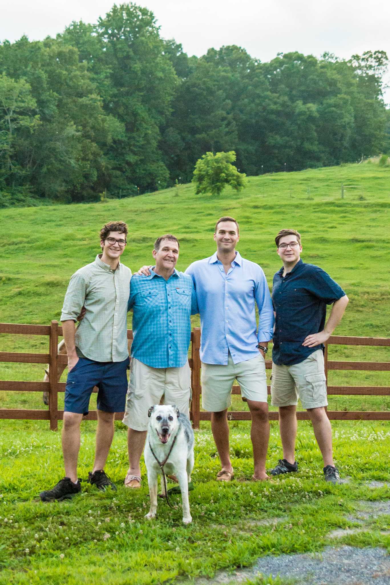 Four young men standing with a white dog in a green pasture at a park near Marietta