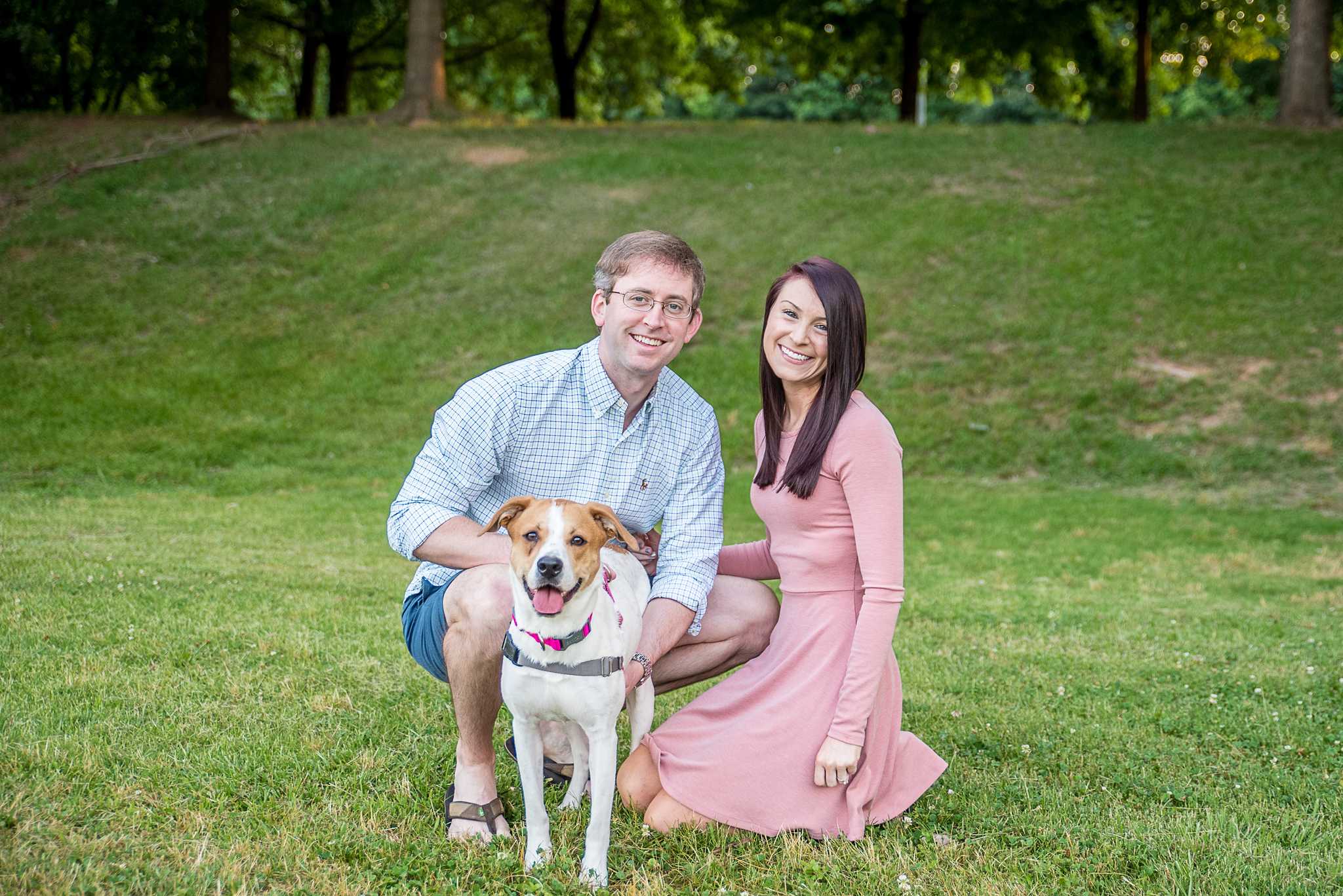 Couple kneeling on the grass with their tan and white hound mix during family photos with their dog at Piedmont Park