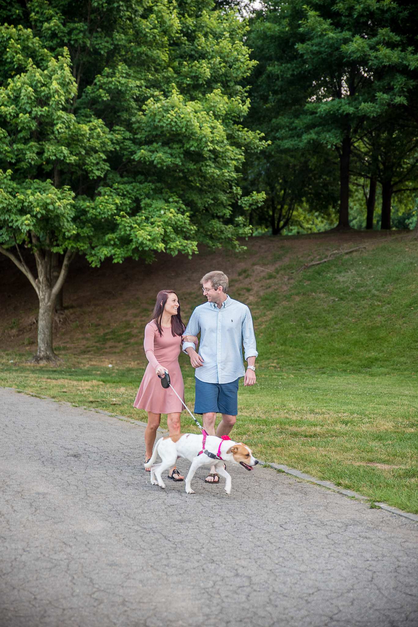 Couple walking their leashed dog along a shaded path at Piedmont Park