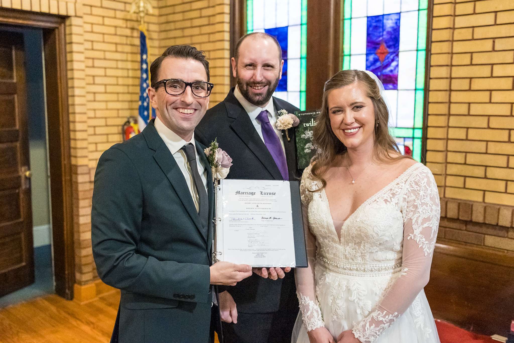 Couple holding their marriage license with the officiant at Fayetteville First United Methodist Church
