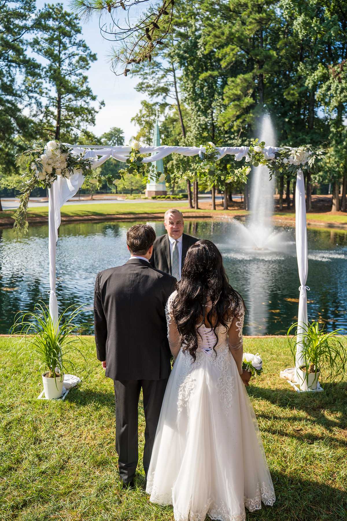 Couple standing beneath a floral arch by the pond at First Baptist Atlanta