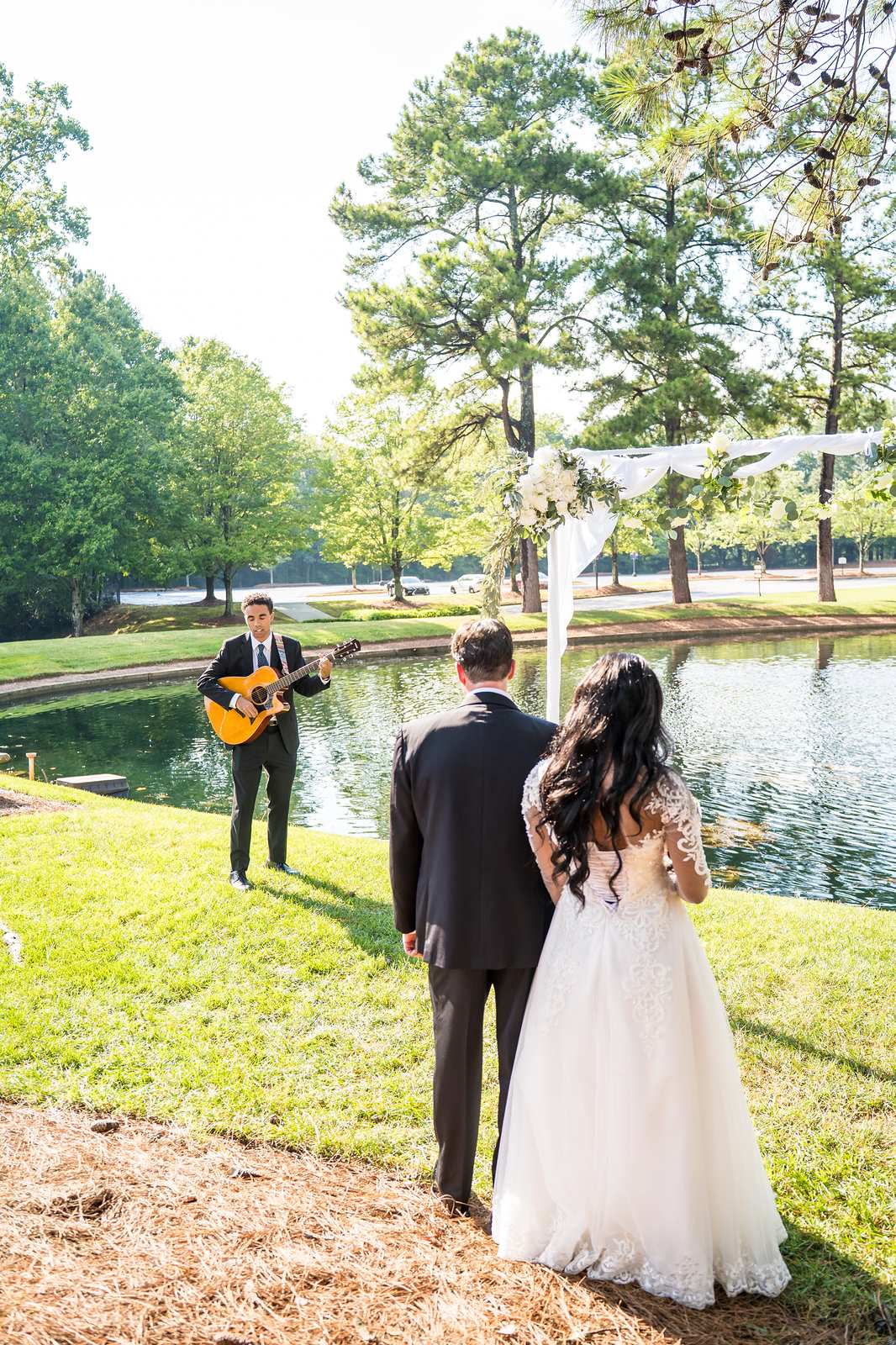 Guitarist and couple by the pond during an outdoor ceremony