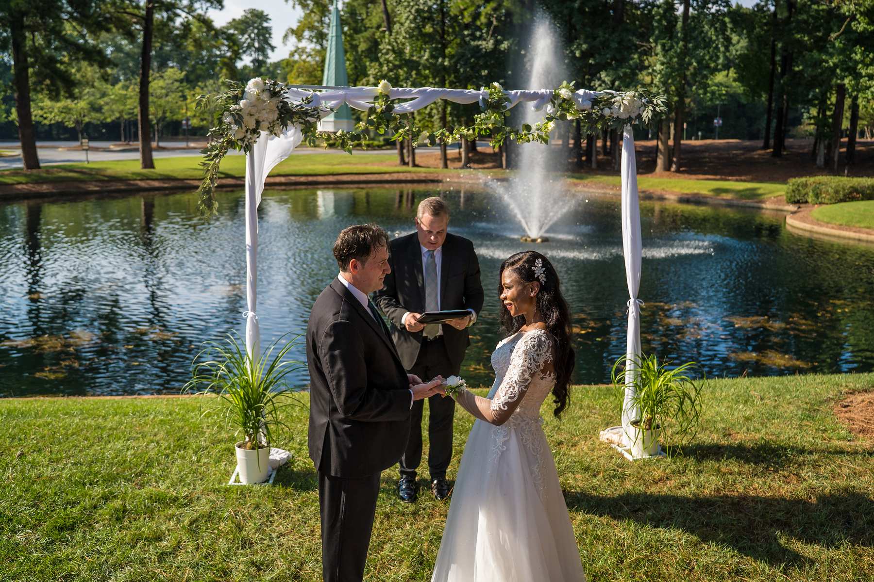 Couple holding hands in front of the fountain during their vows