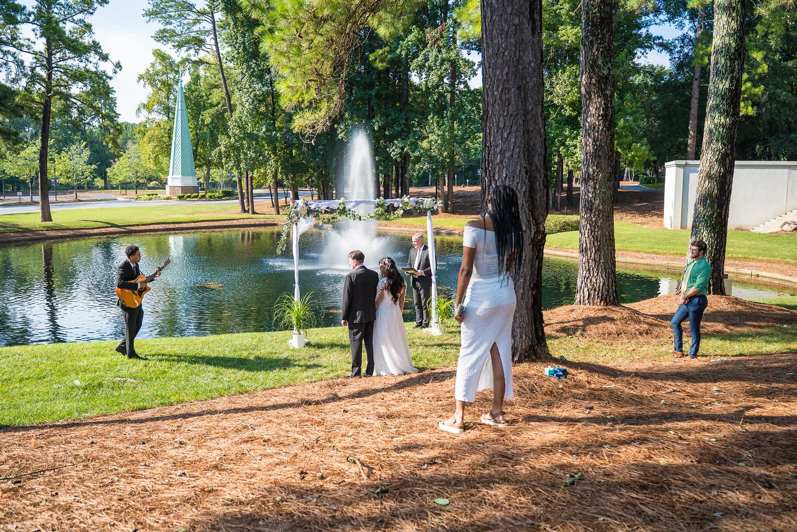 Guests and guitarist watching an outdoor ceremony on the lawn