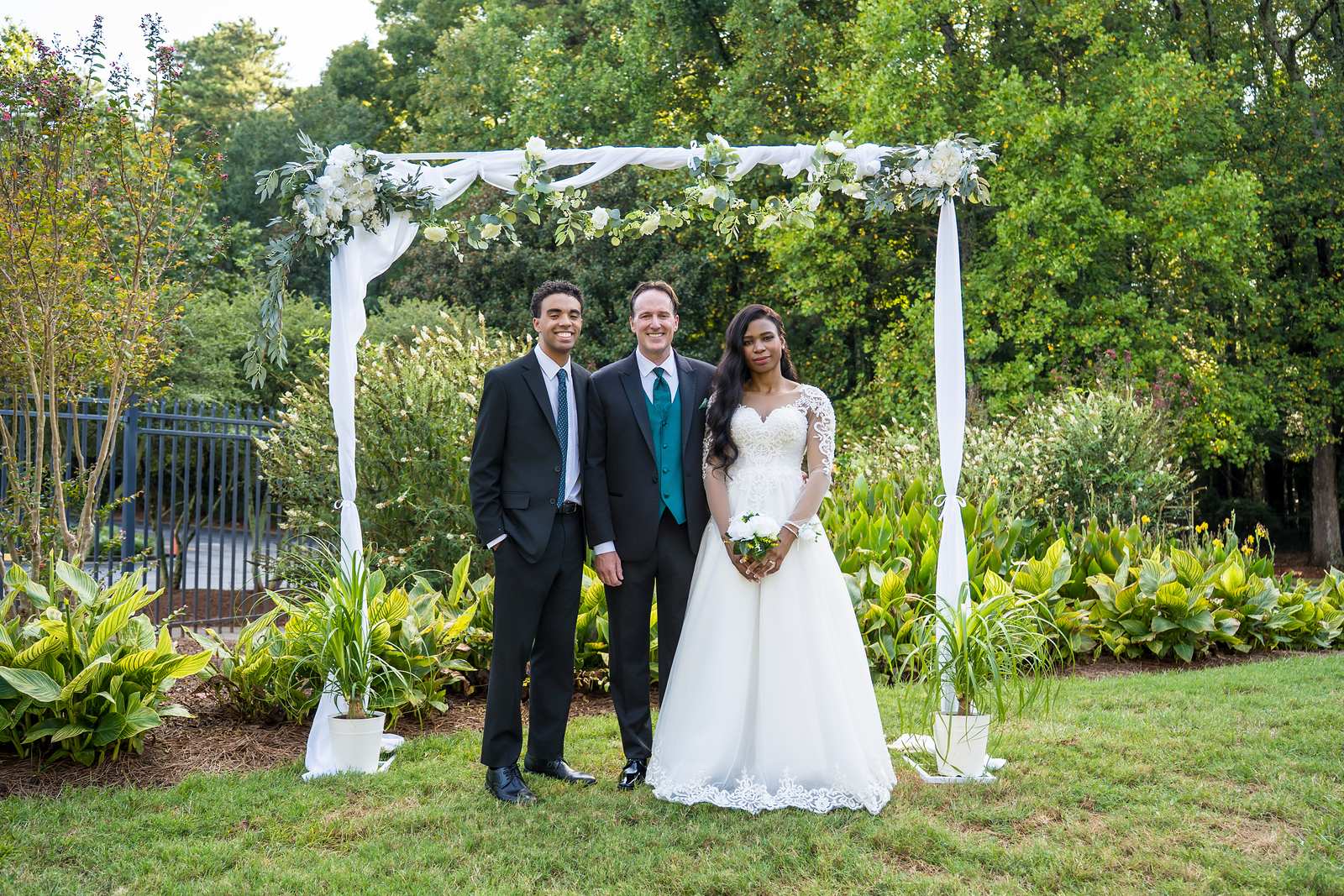 Couple with the officiant under the arch after their ceremony