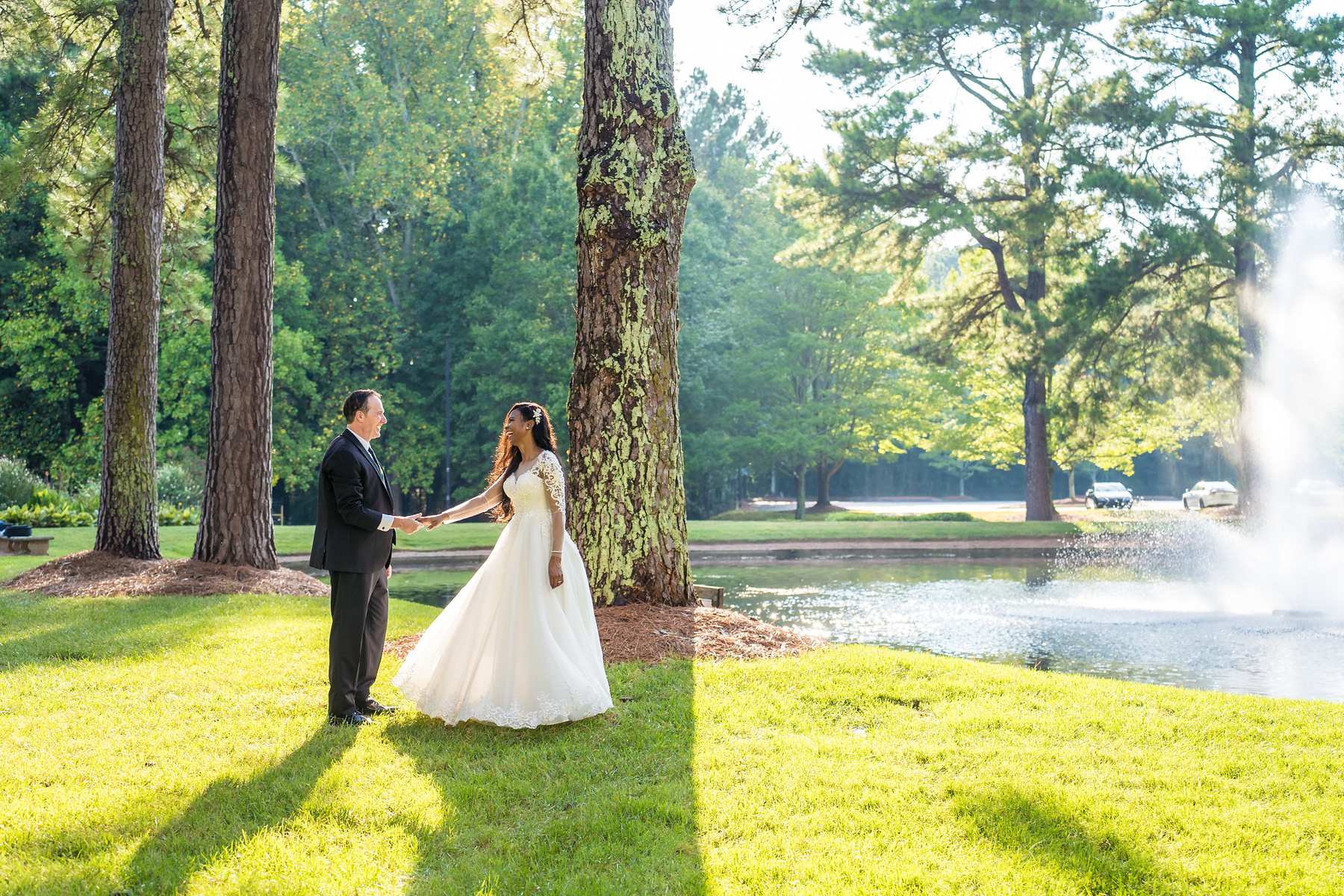 Couple facing each other on the lawn with the fountain in the distance
