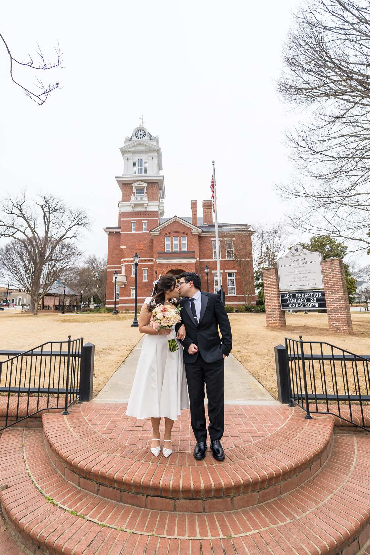 Couple kissing on the front steps below the Gwinnett Historic Courthouse clock tower
