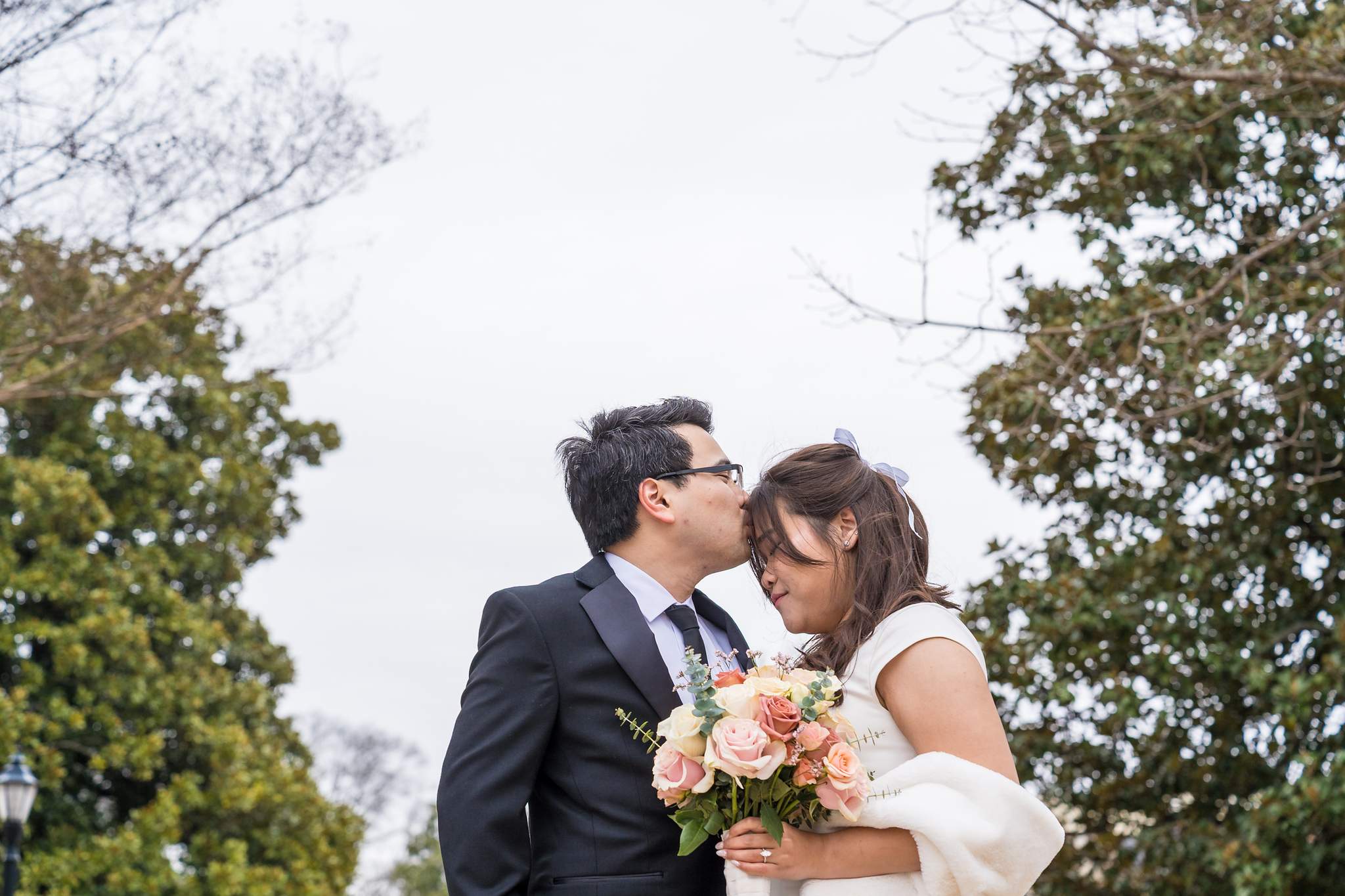 Bride holding a blush rose bouquet beside the groom outside the Gwinnett Historic Courthouse