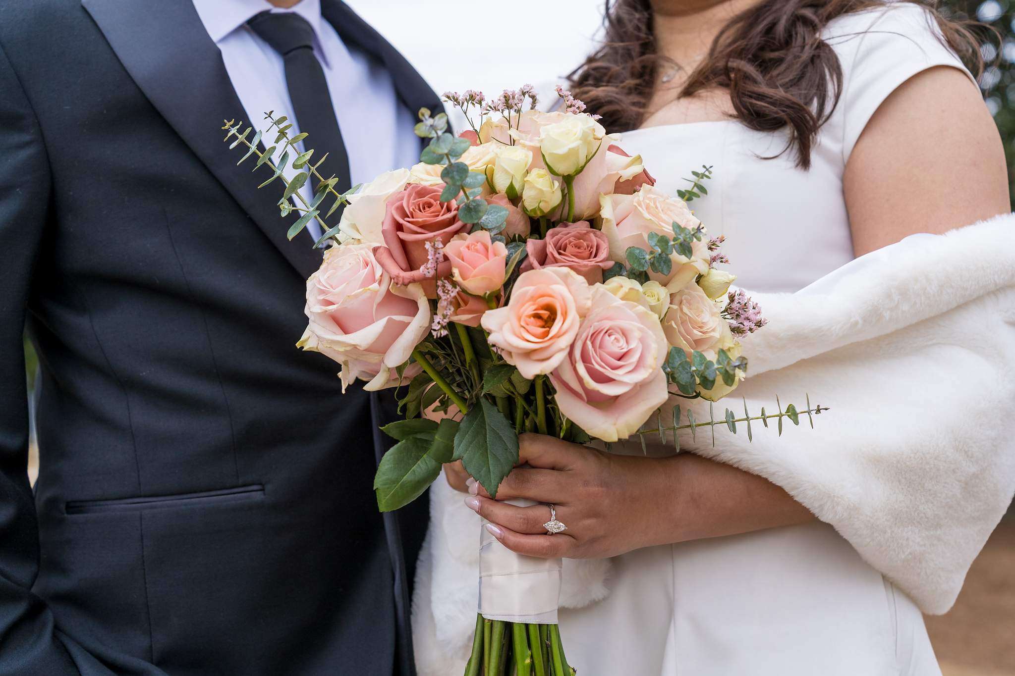 Bride in a white faux fur wrap holding a blush rose bouquet at a winter courthouse wedding
