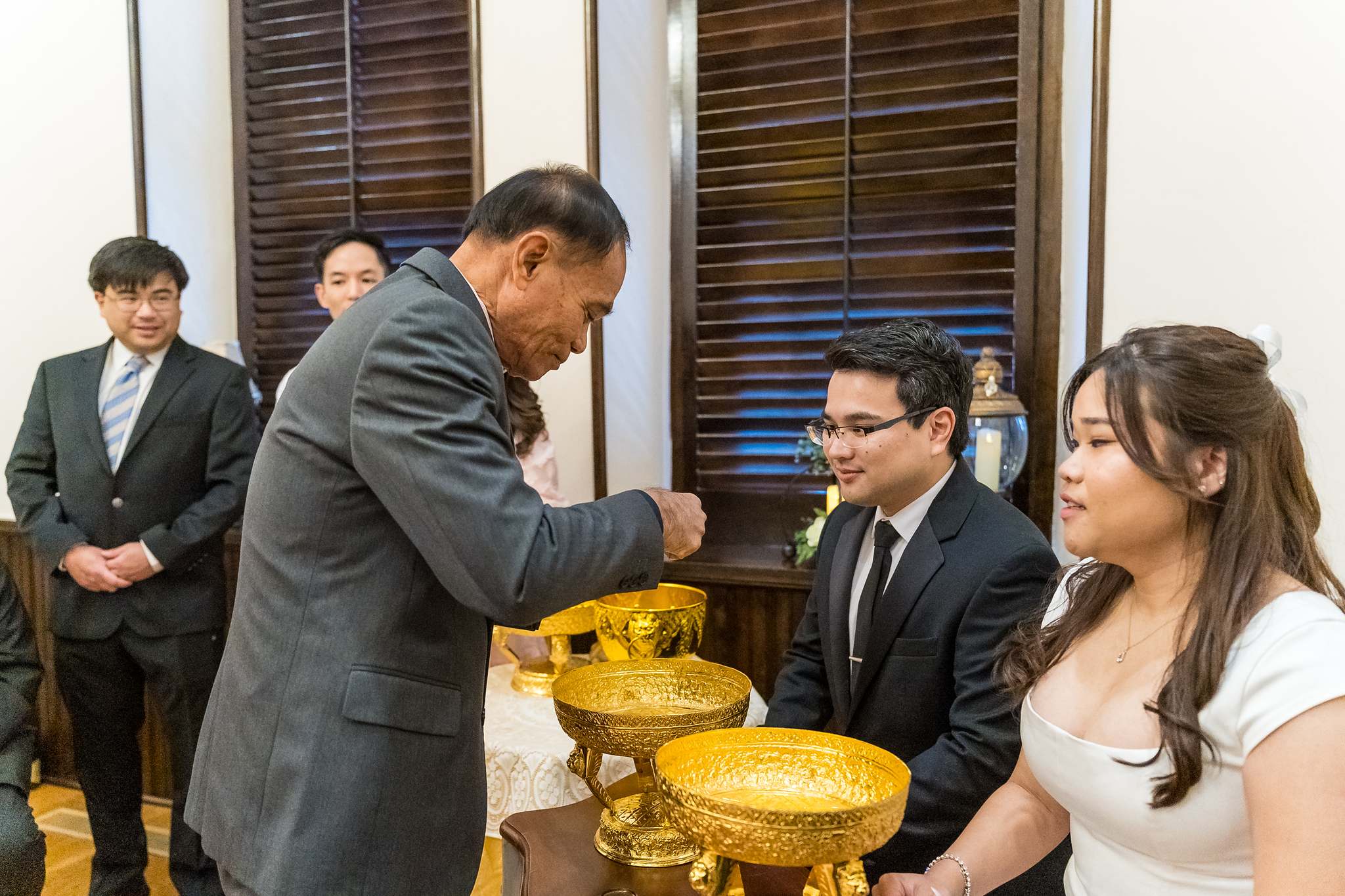 Family member pouring water over the couple’s hands during a blessing at a small courthouse wedding