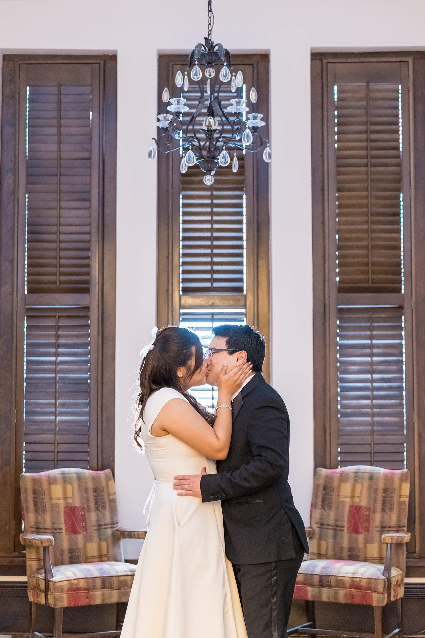 Couple kissing by tall shuttered windows inside the Gwinnett Historic Courthouse