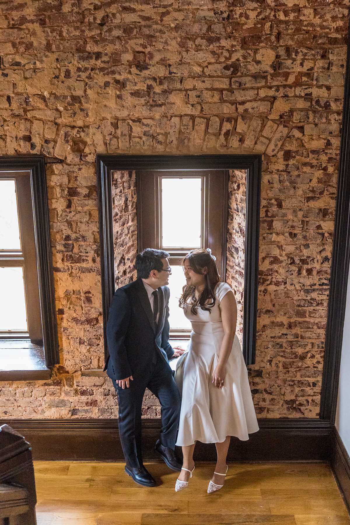 Couple by a window framed with exposed brick at the Gwinnett Historic Courthouse