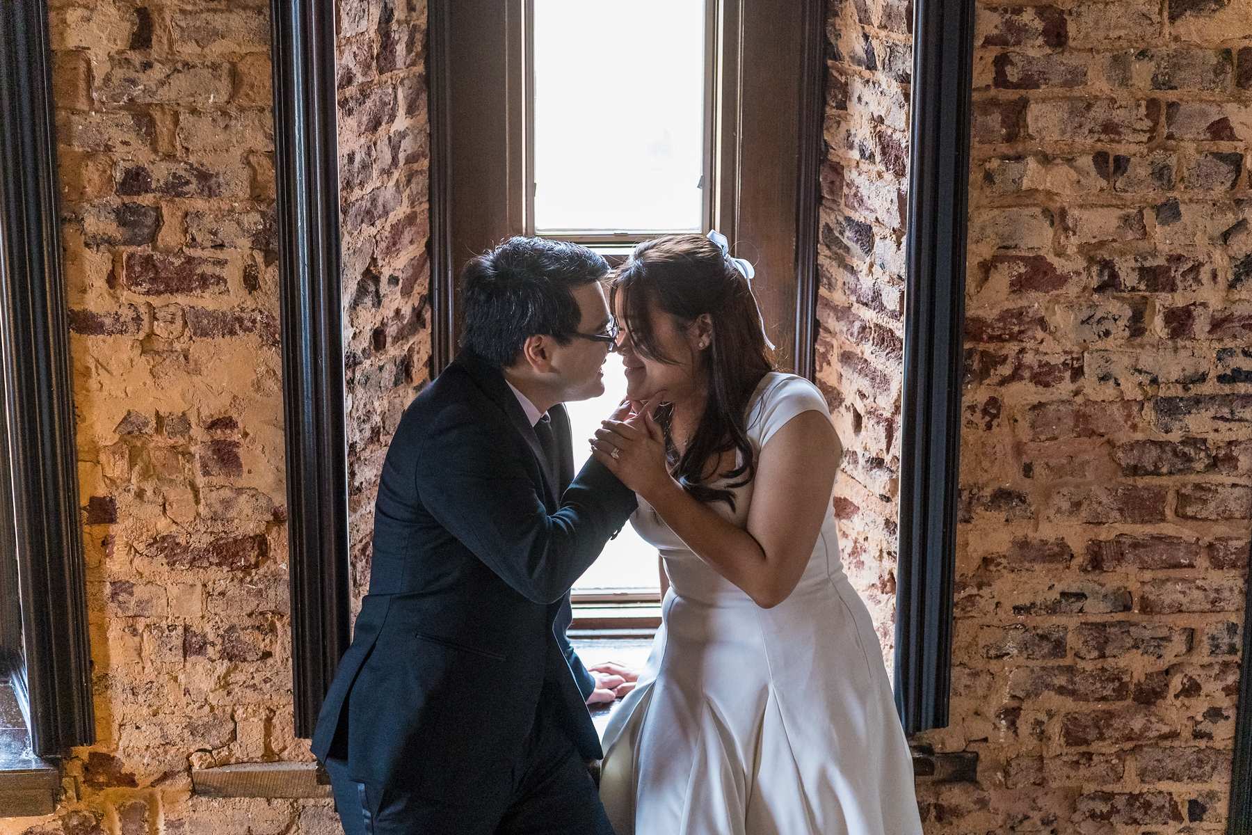 Couple sharing a moment by an exposed brick window at the Gwinnett Historic Courthouse