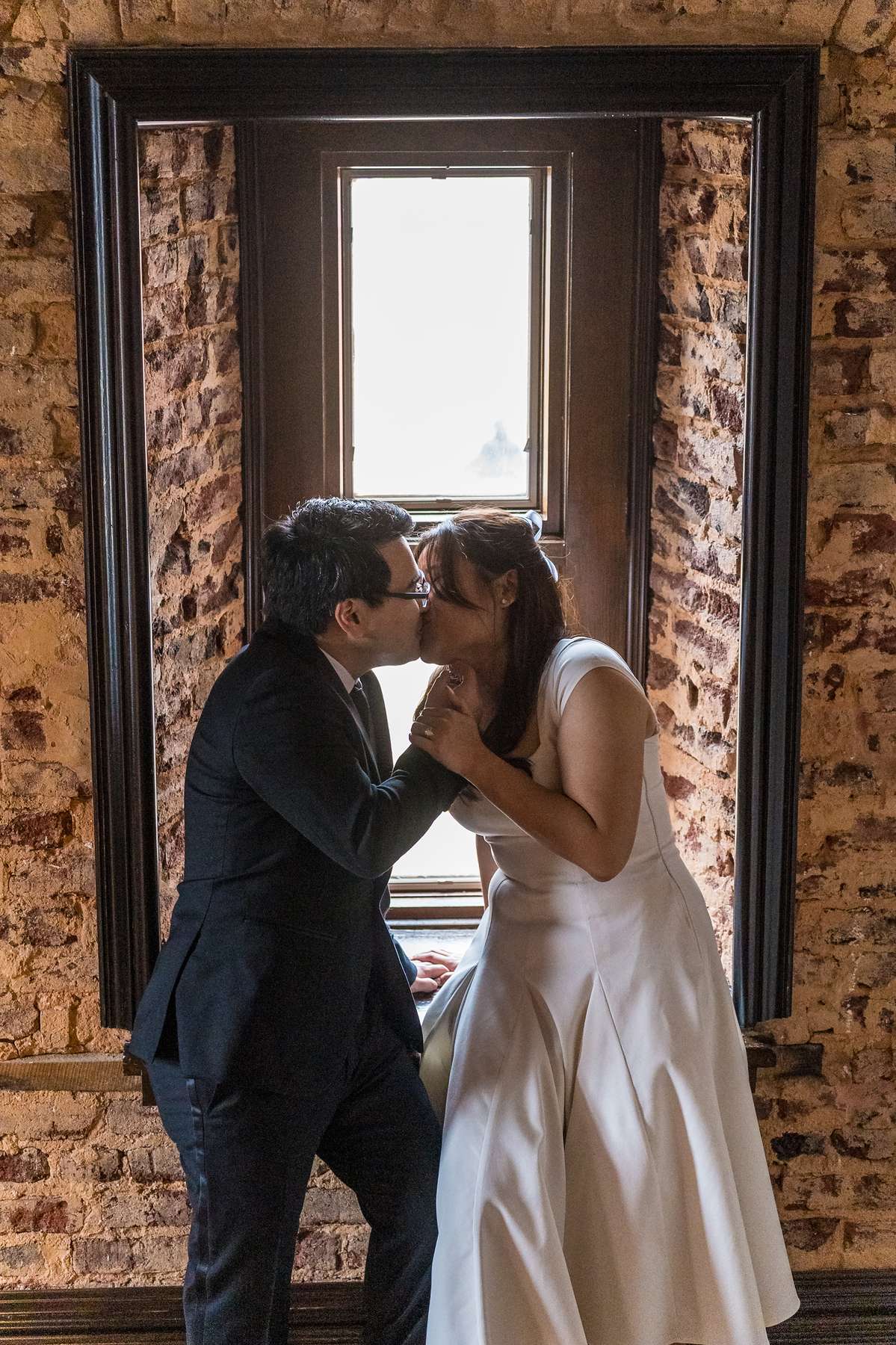 Couple kissing in a brick window frame inside the Gwinnett Historic Courthouse