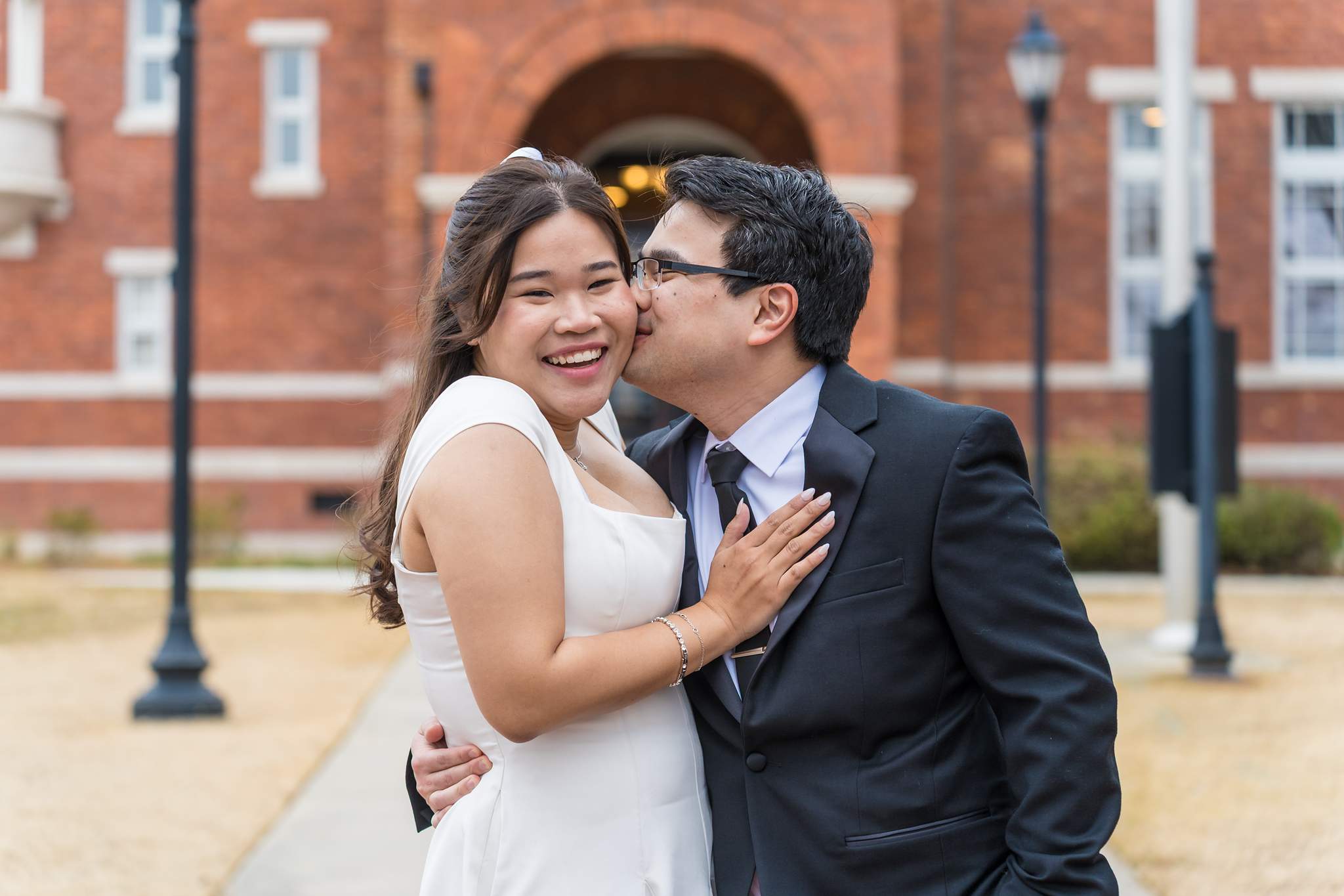 Bride in a fitted white dress and groom in a dark suit outside the Gwinnett Historic Courthouse