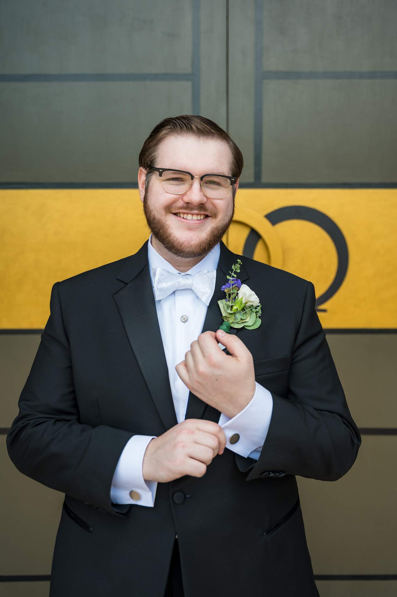 Groom adjusting his boutonniere at the church doors of Immaculate Heart of Mary