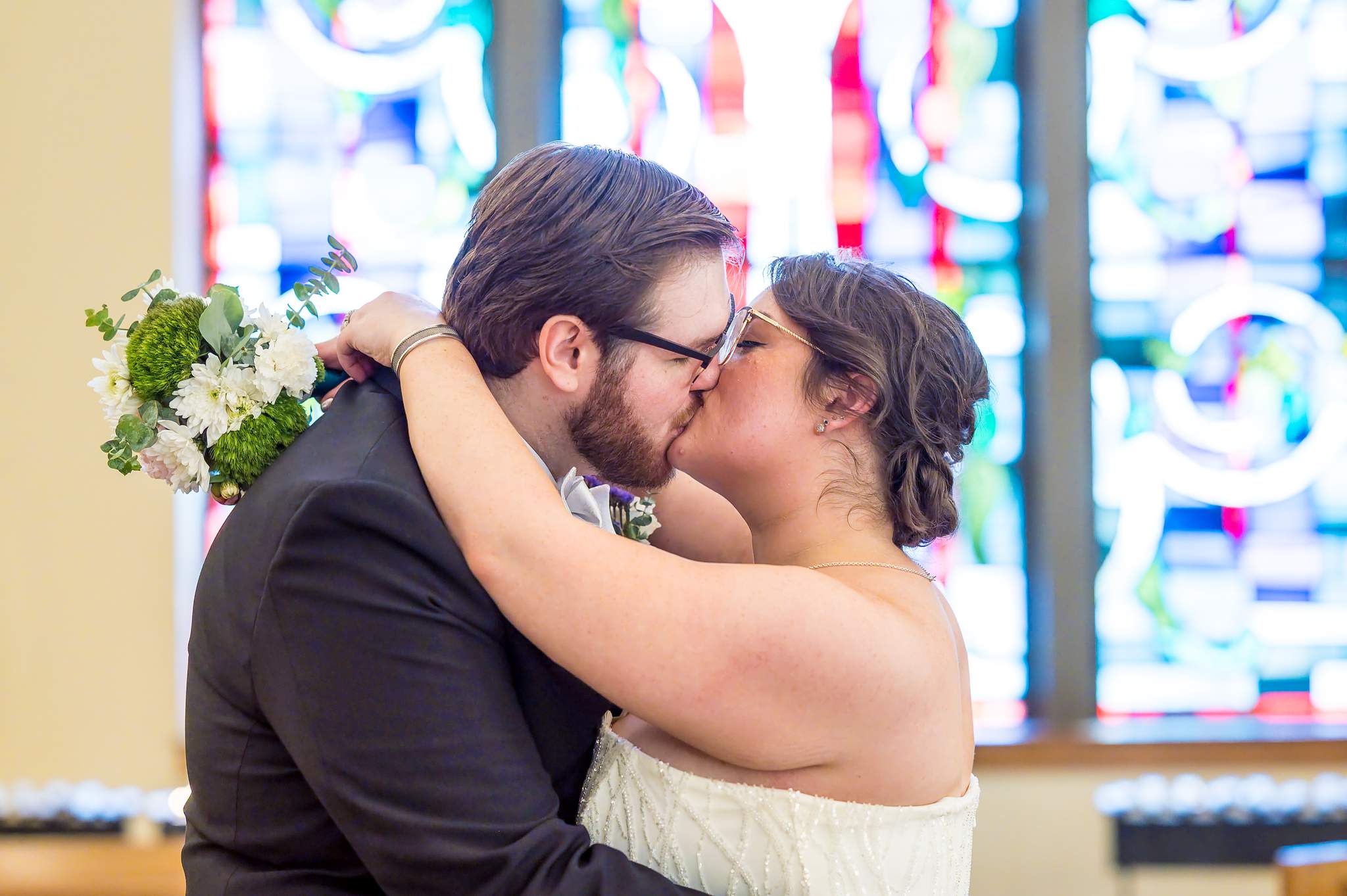 Couple kissing in front of stained glass at Immaculate Heart of Mary in Atlanta