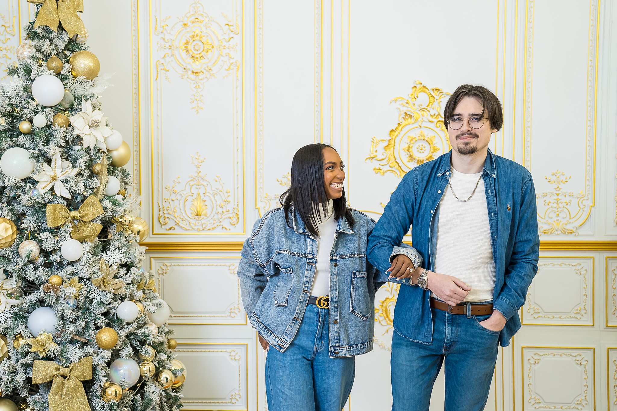 Couple in denim laughing beside a Christmas tree at Luxe Galore Studios Atlanta