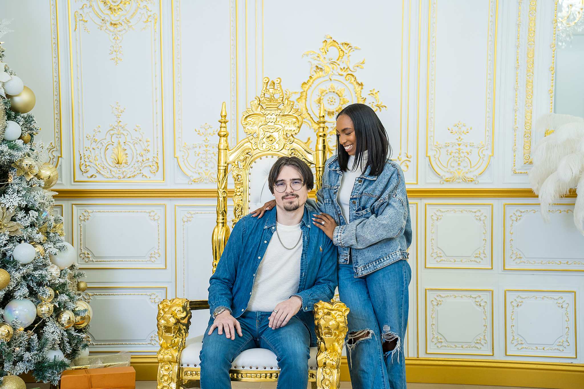Couple in denim with a gold throne chair and Christmas tree at Luxe Galore