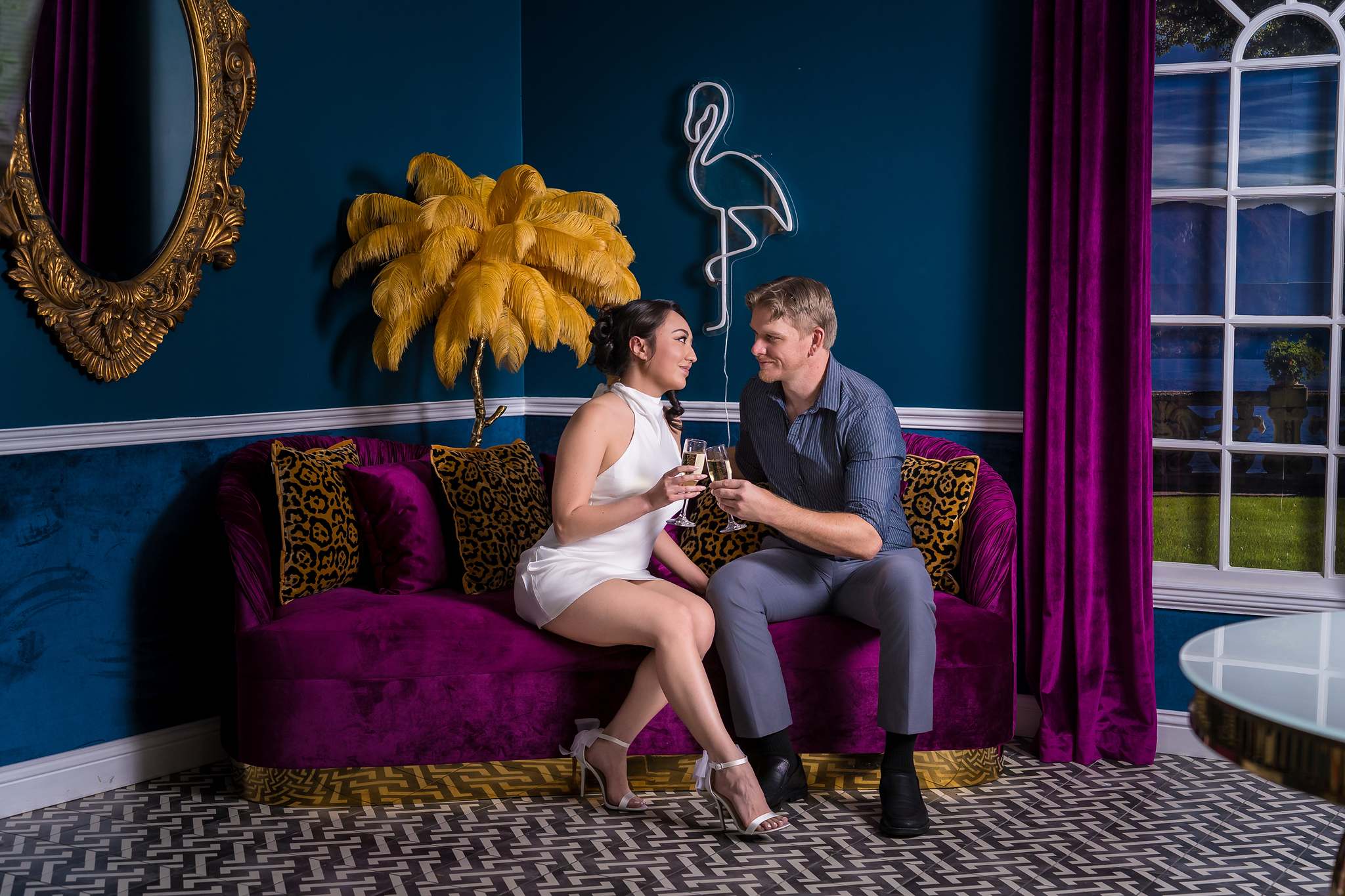 Couple on a plum velvet sofa with golden feather decor at Luxe Galore