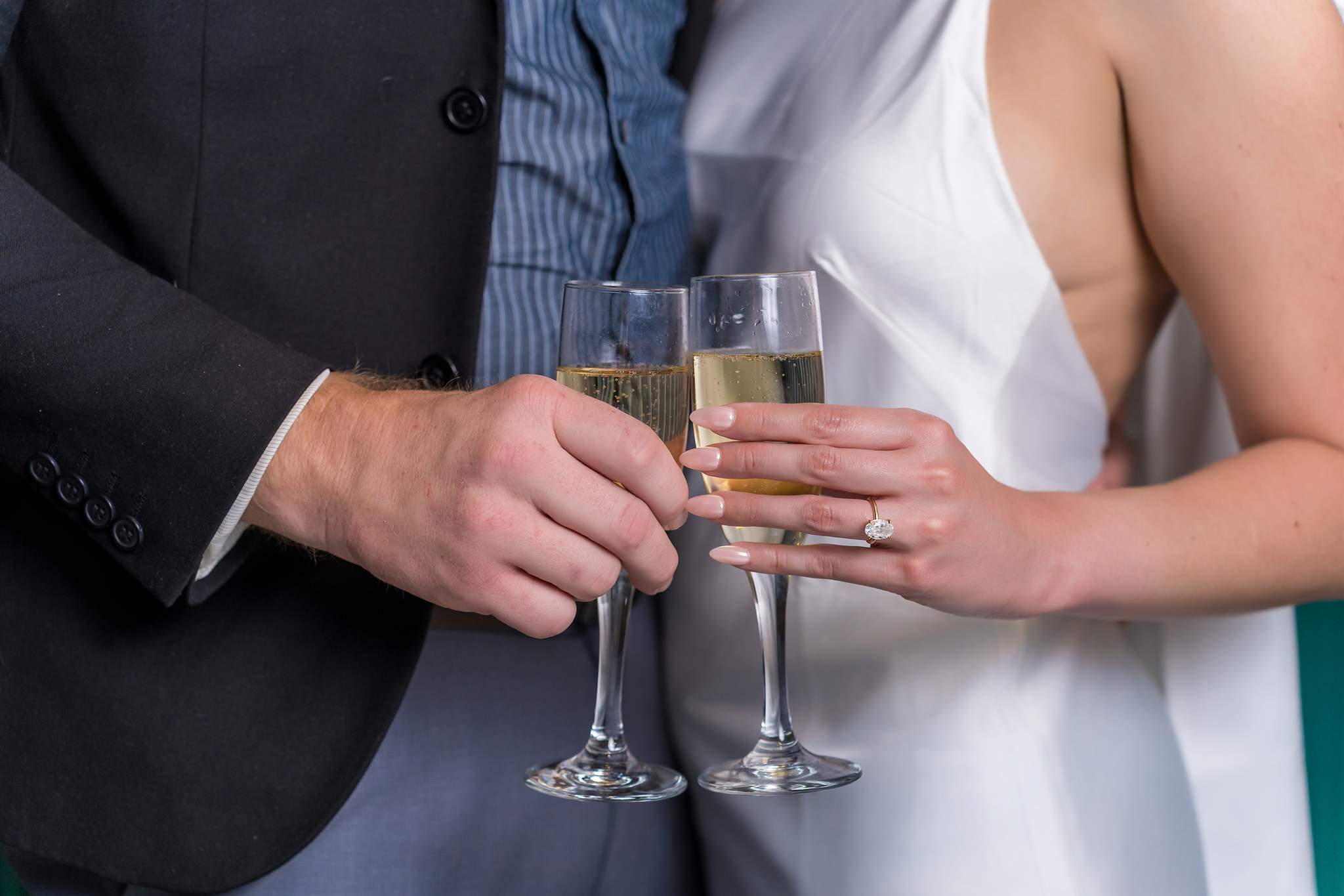 Close-up of a couple holding champagne flutes with an engagement ring