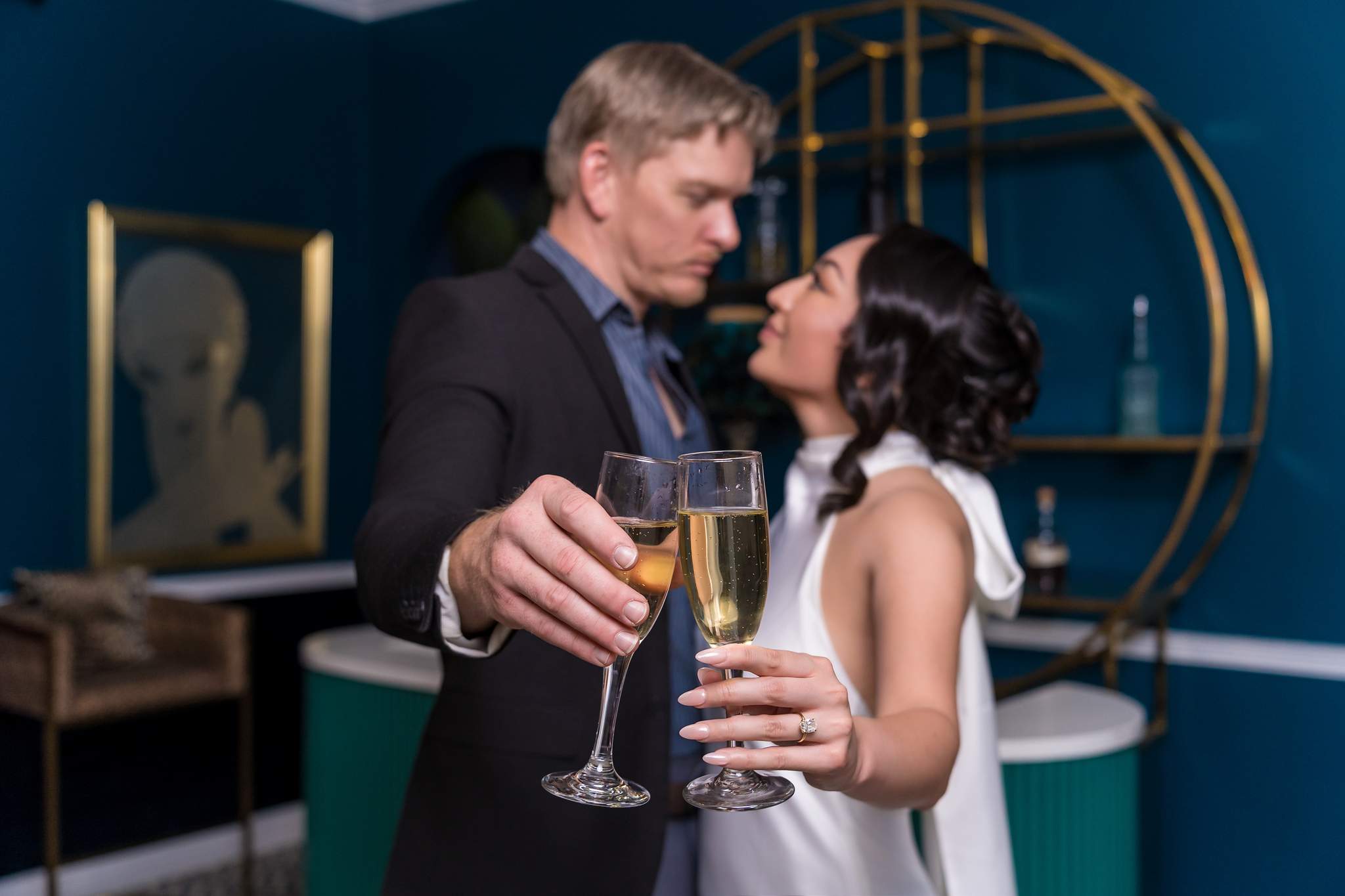 Couple toasting with champagne on a teal set at Luxe Galore Studios Atlanta
