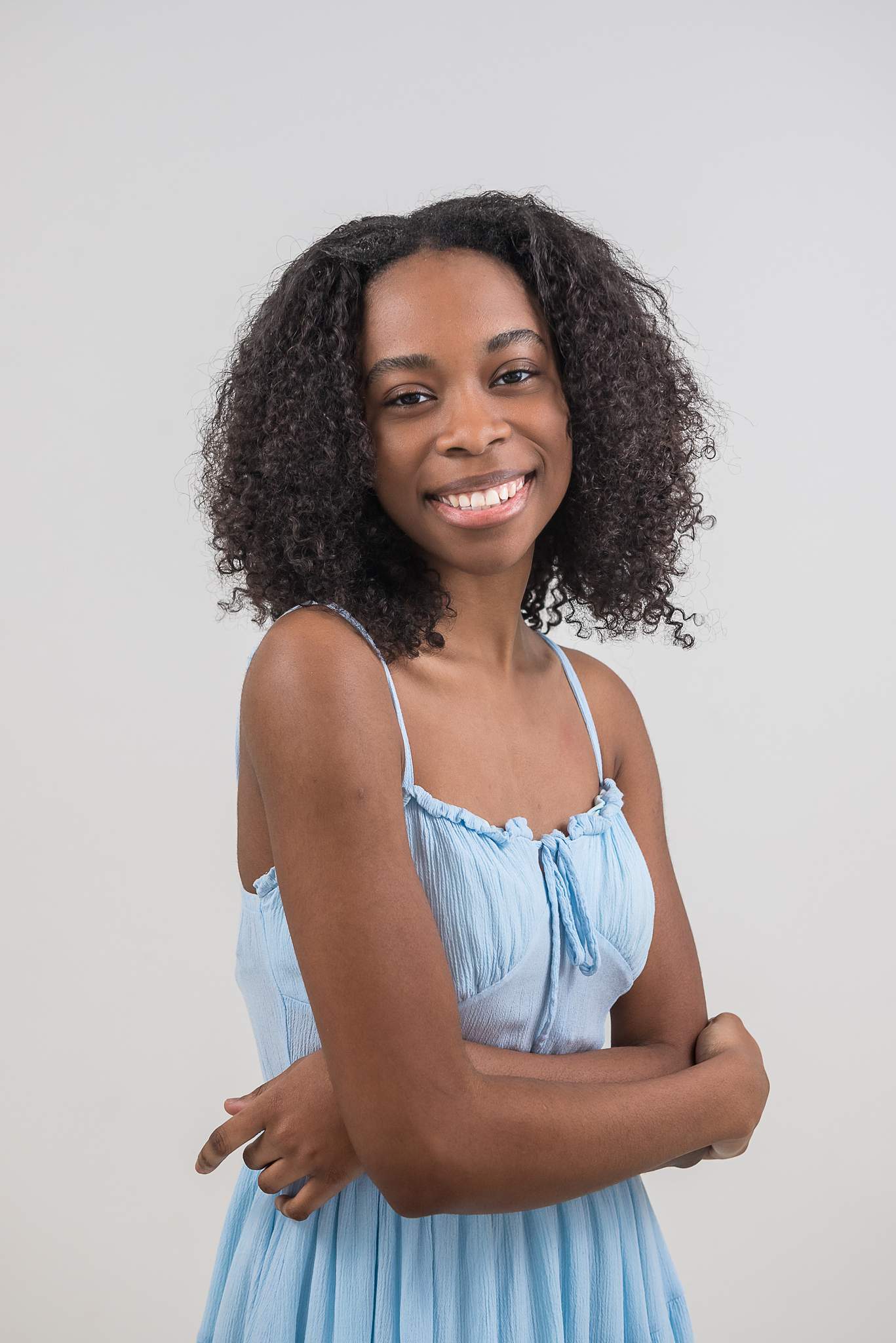 Woman with arms crossed in a light blue dress at White Wall Studio