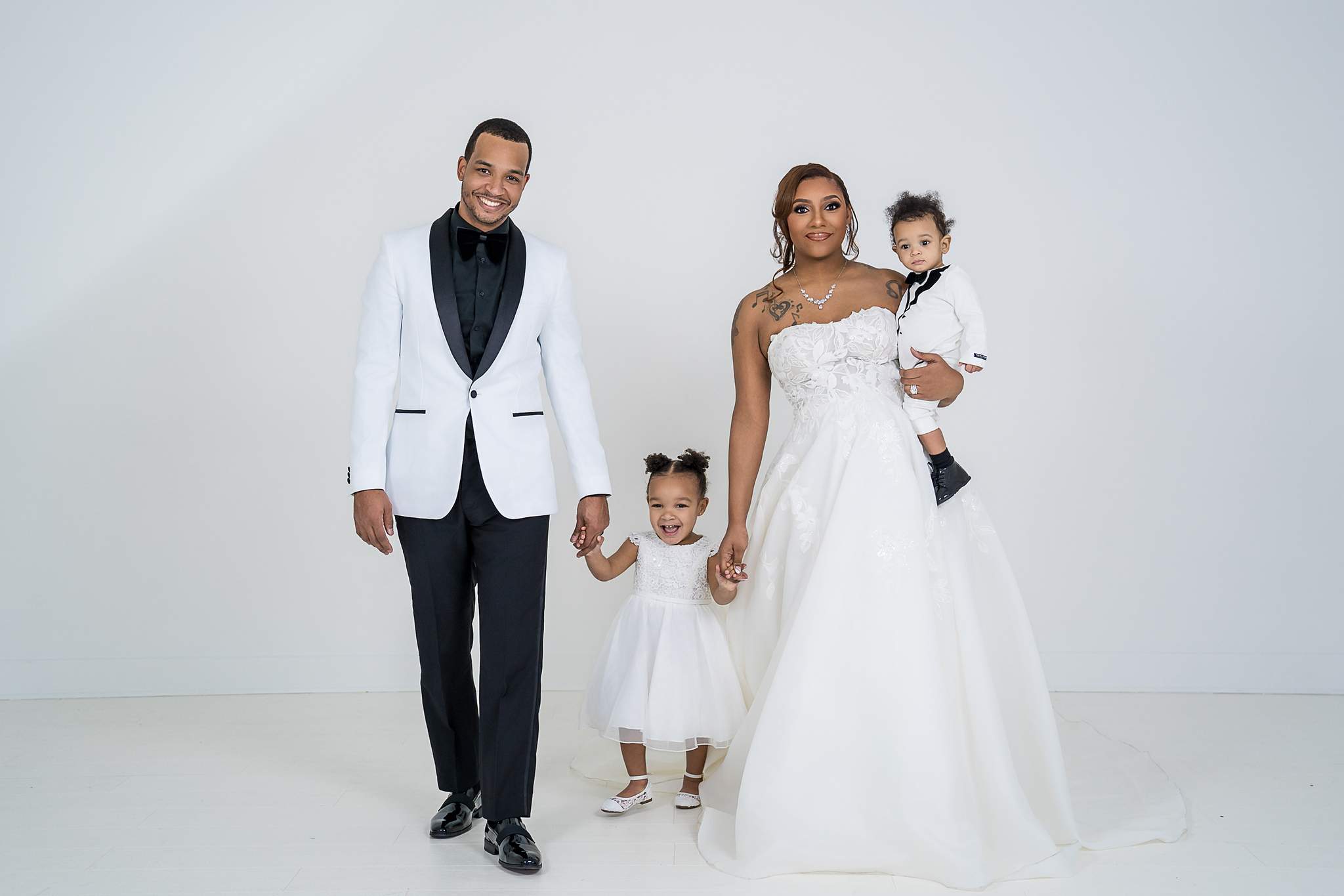 Family in wedding attire with their young daughter at White Wall Studio