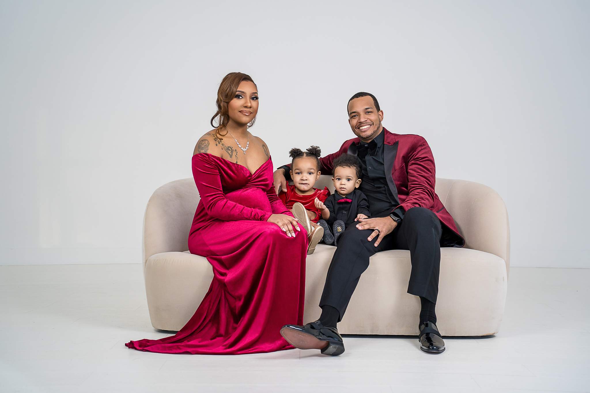 Family in red and black on a cream sofa at White Wall Studio