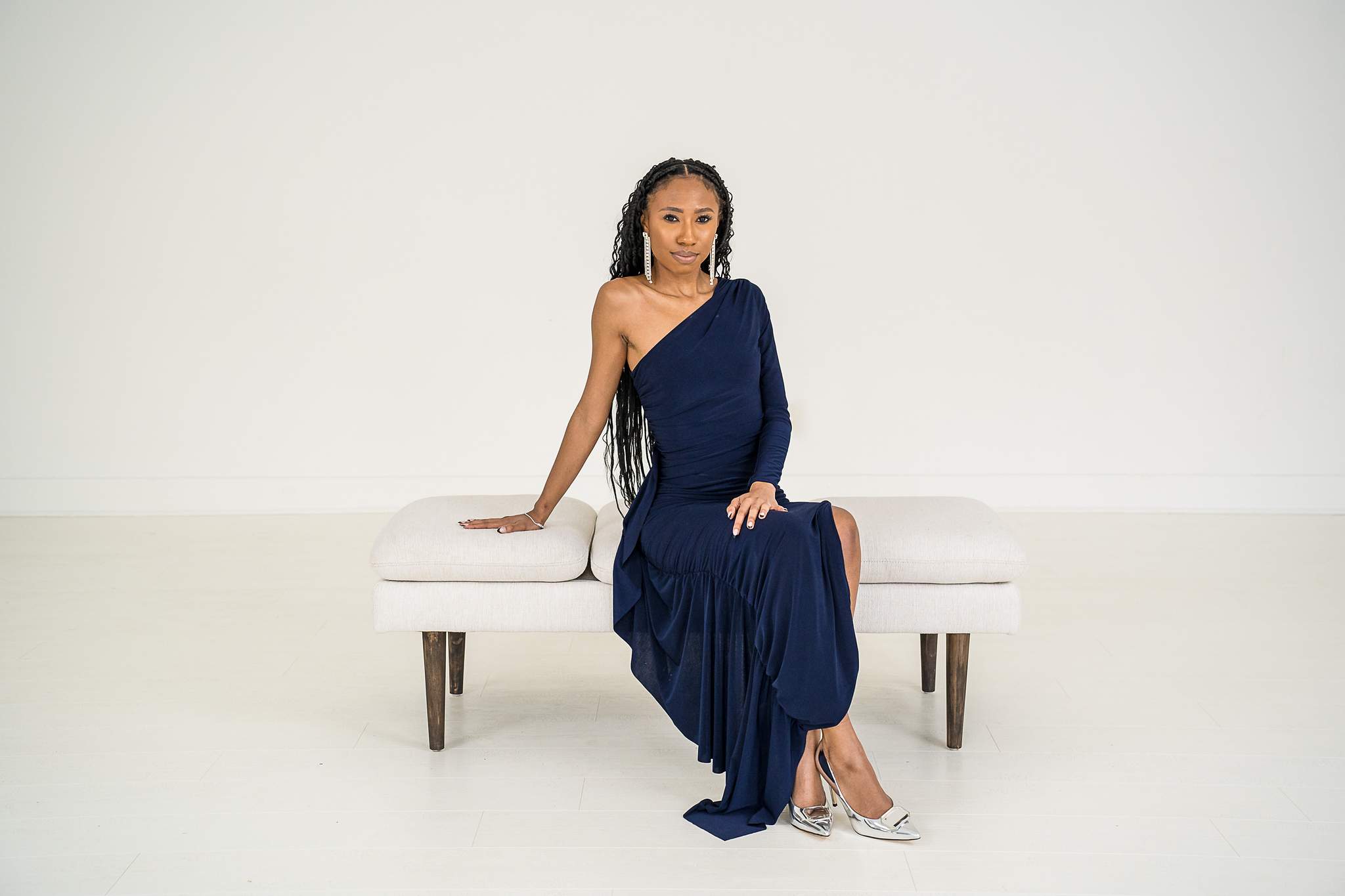 Woman in a navy gown seated on a white bench at White Wall Studio Woodstock