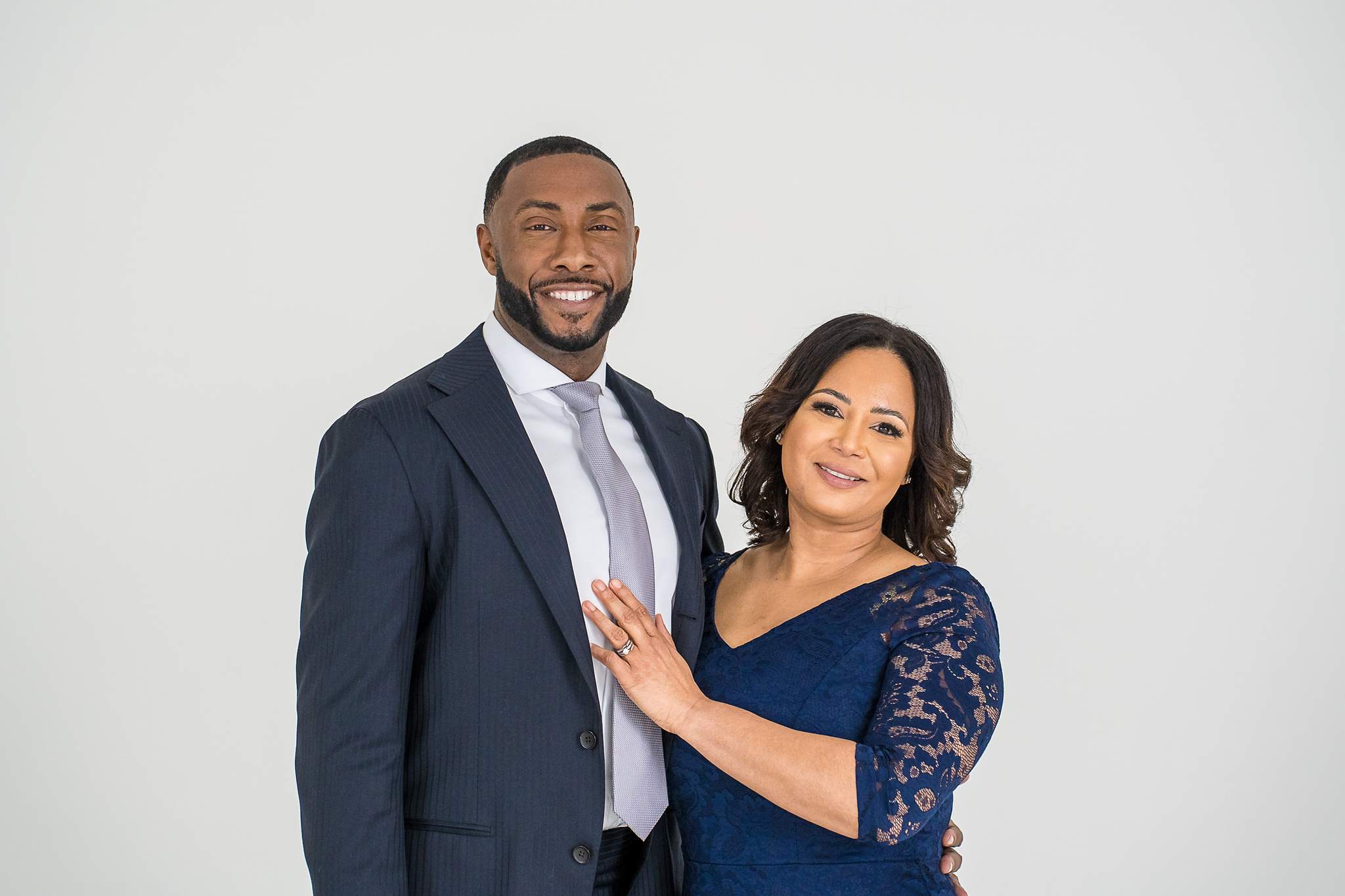 Man in a navy suit with a family member in a navy lace dress at White Wall Studio