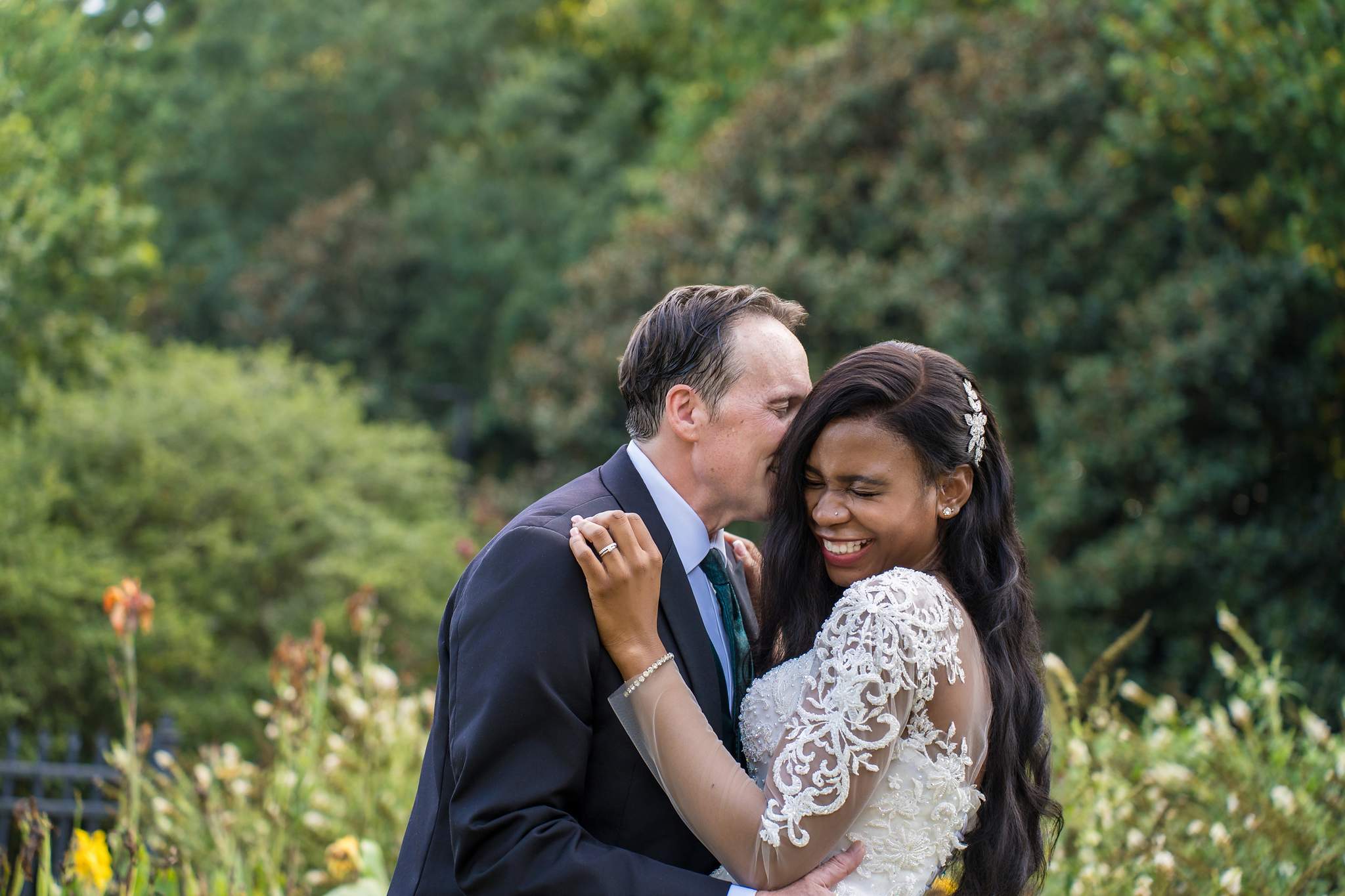 Groom kissing the bride’s forehead during interracial wedding portraits in Atlanta