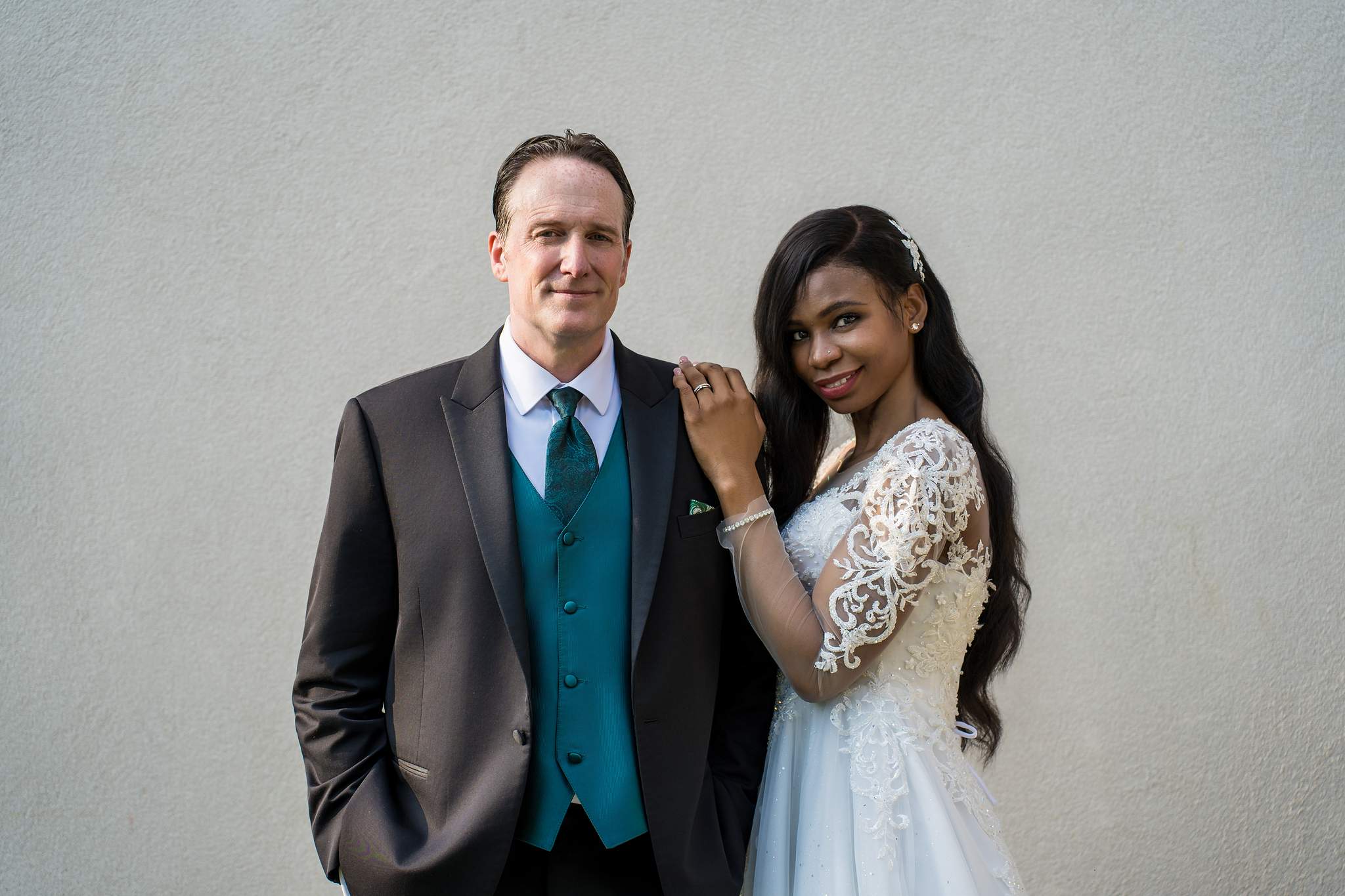 Interracial wedding portrait against a light stone wall in Atlanta