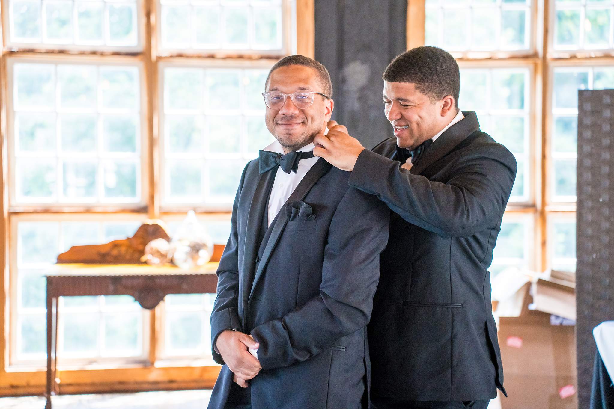Groom getting ready with a groomsman by the windows at Ivy Hall at Roswell Mill