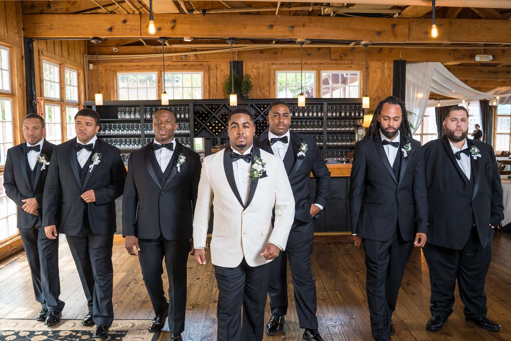 Groom and groomsmen in tuxedos inside Ivy Hall at Roswell Mill