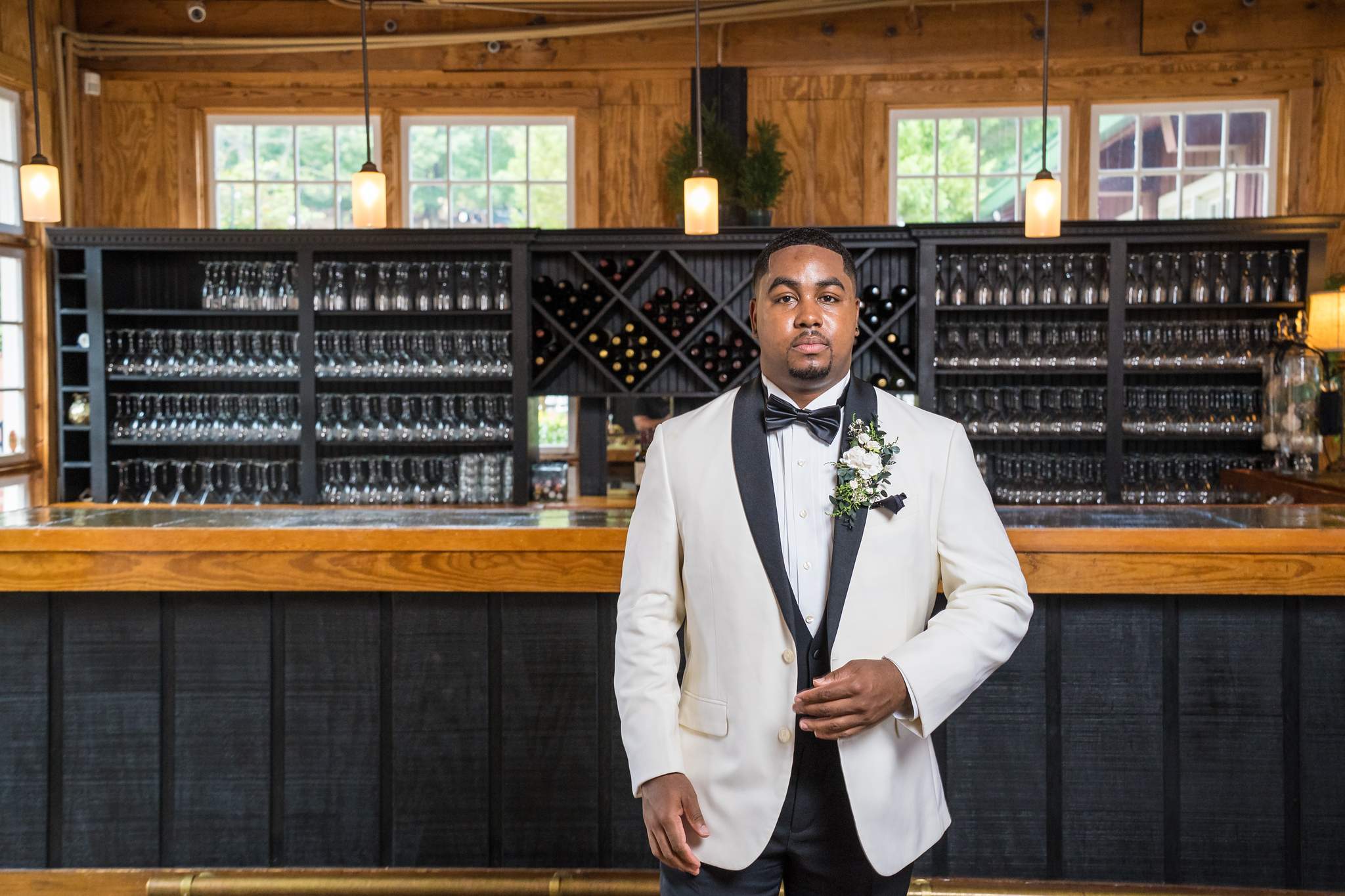 Groom in a white dinner jacket by the bar at Ivy Hall at Roswell Mill