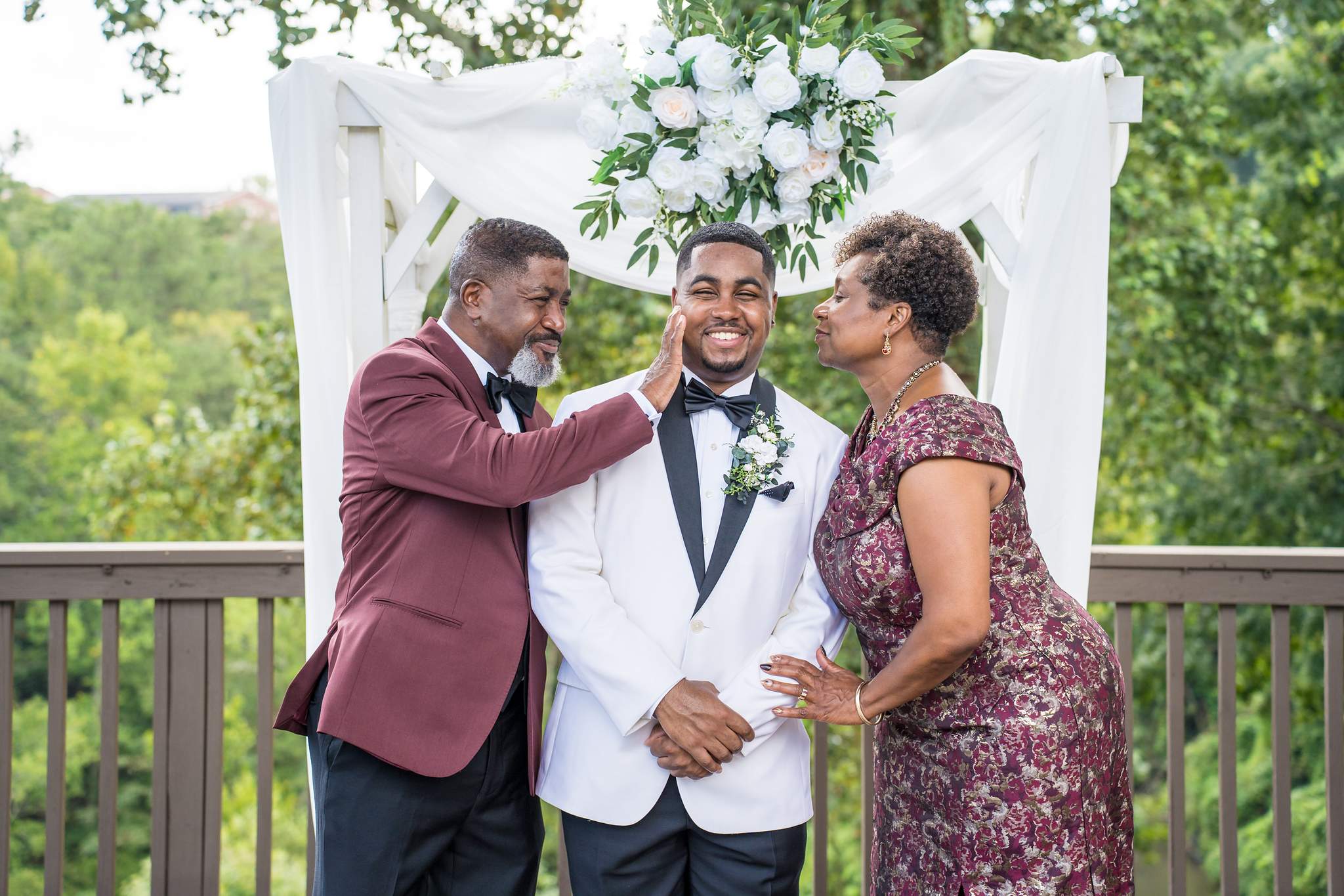 Groom with family under the ceremony arbor on the deck at Ivy Hall at Roswell Mill